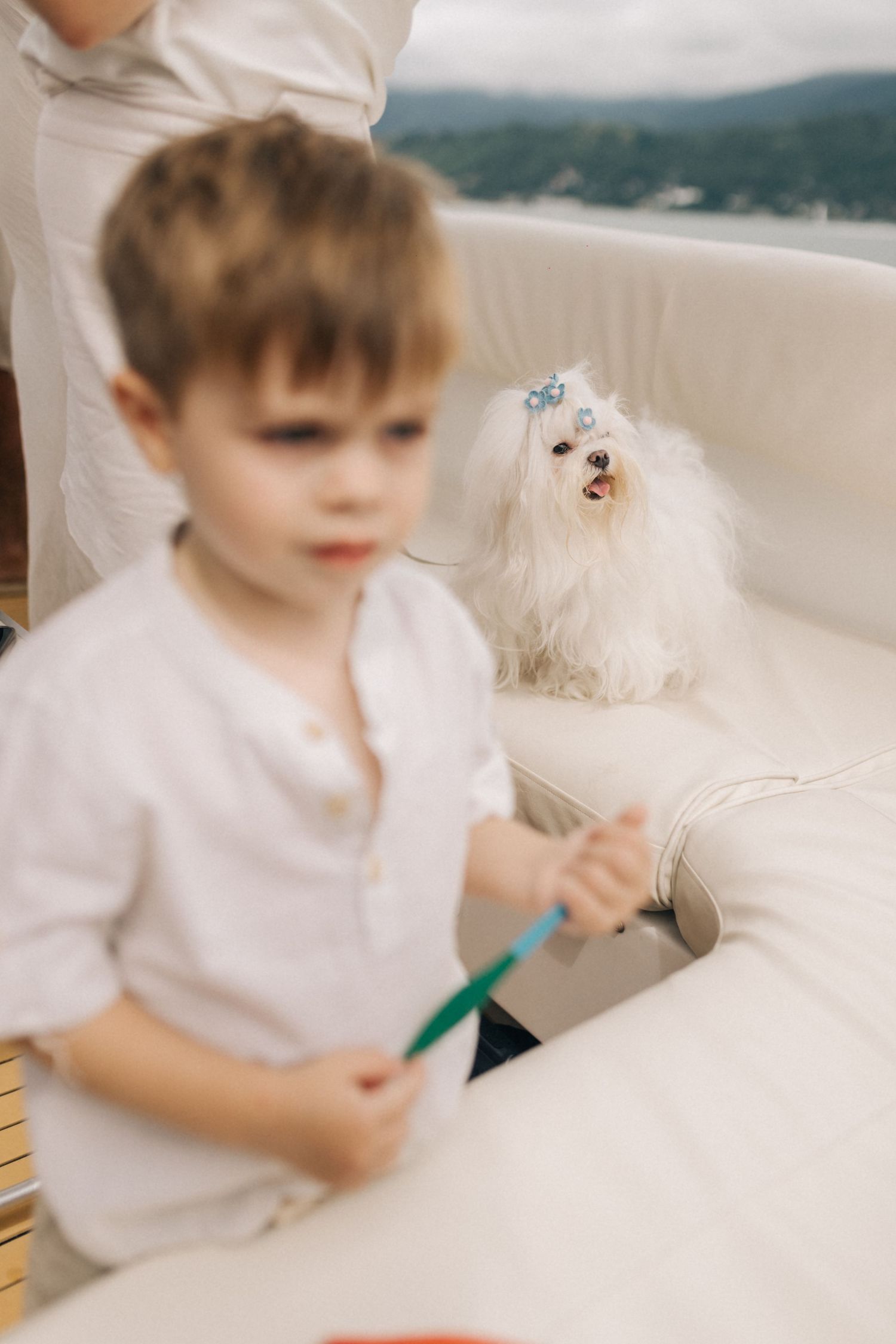 A small child in a white shirt sits on a light colored couch or chair.