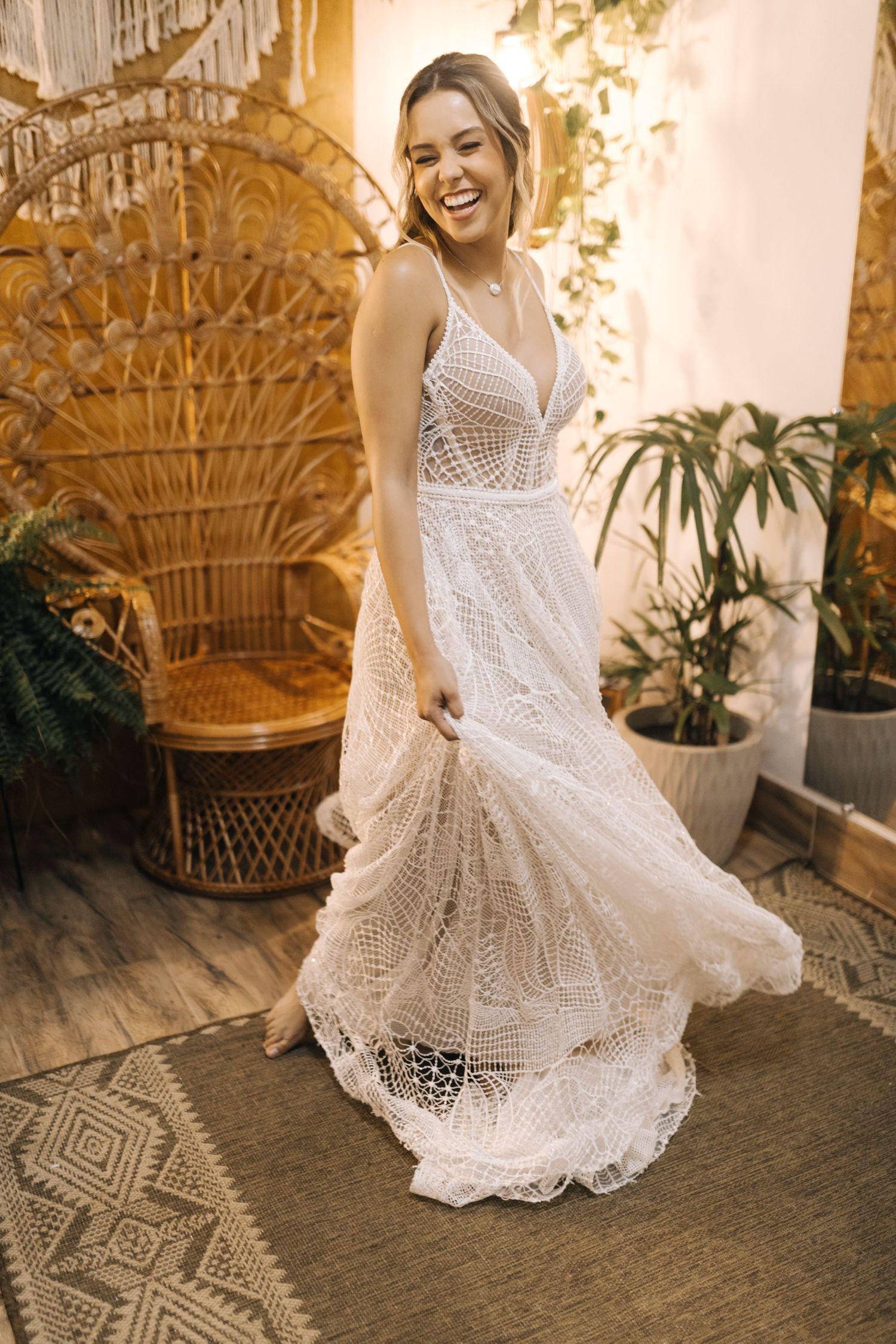 Wedding dress with delicate lace detail displayed against a patterned rug and wicker furniture.