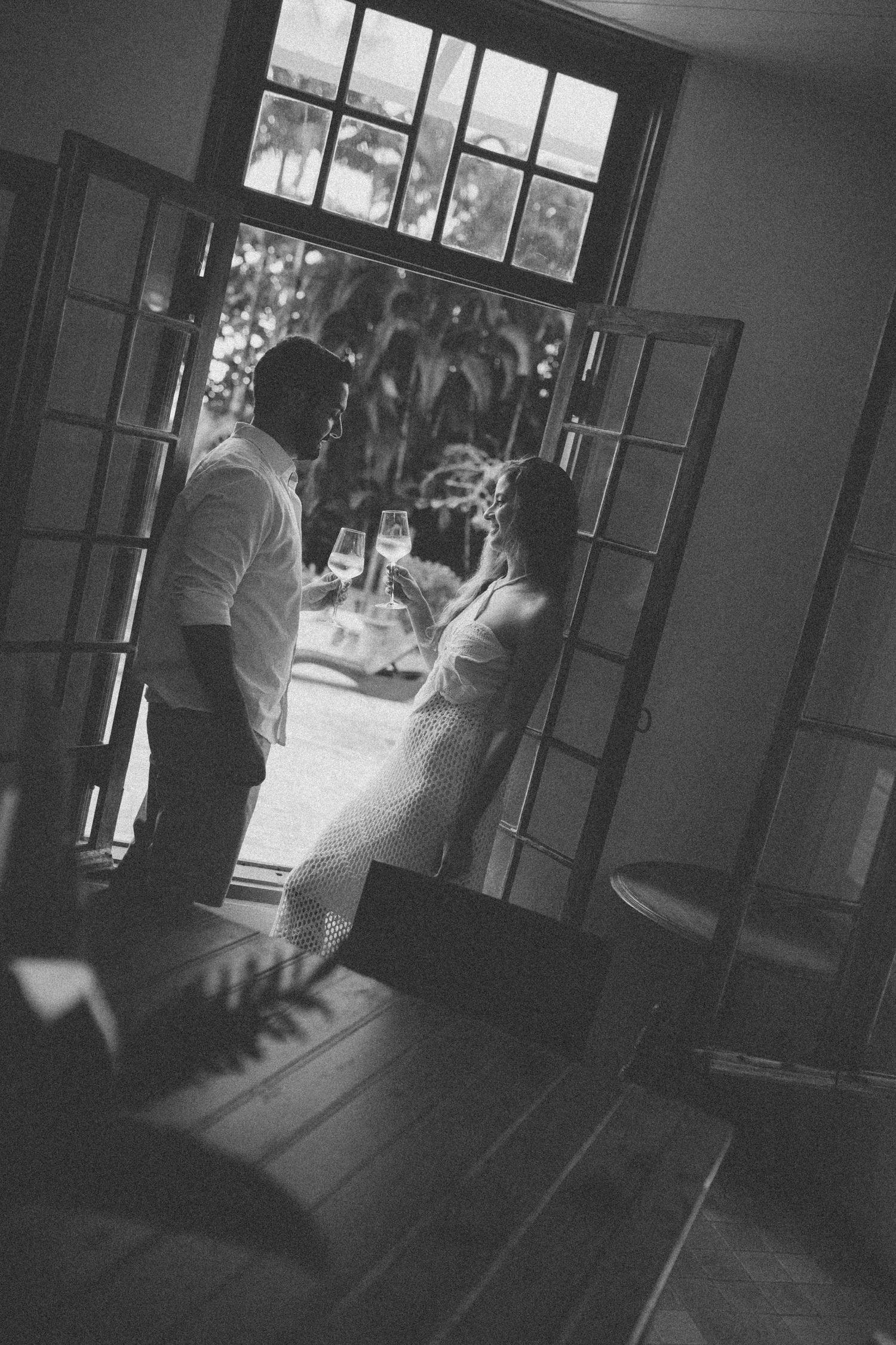 Black and white photo of dancing silhouettes in front of large windows with natural light.