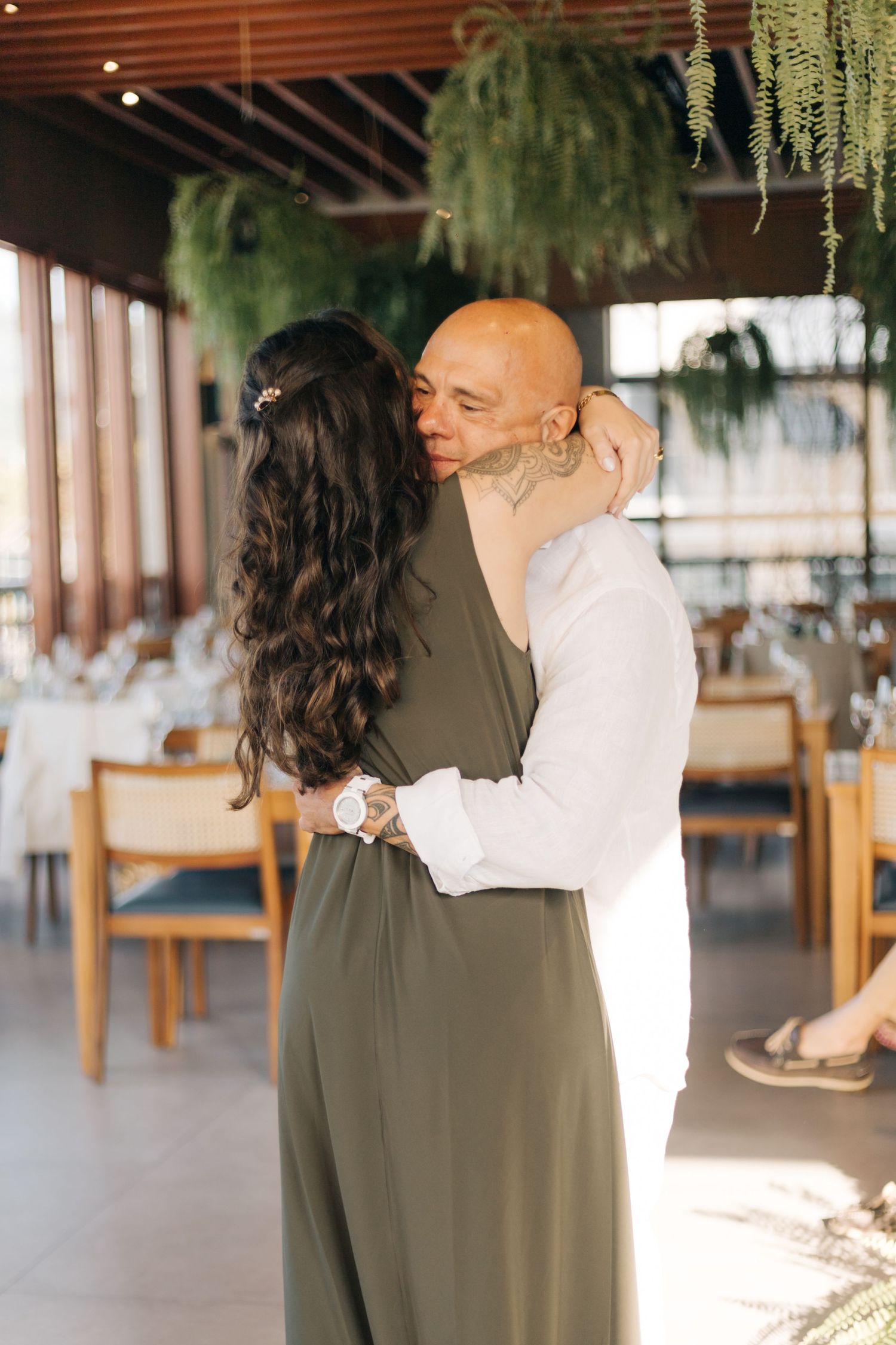 Couple sharing intimate moment under hanging plants at indoor venue.