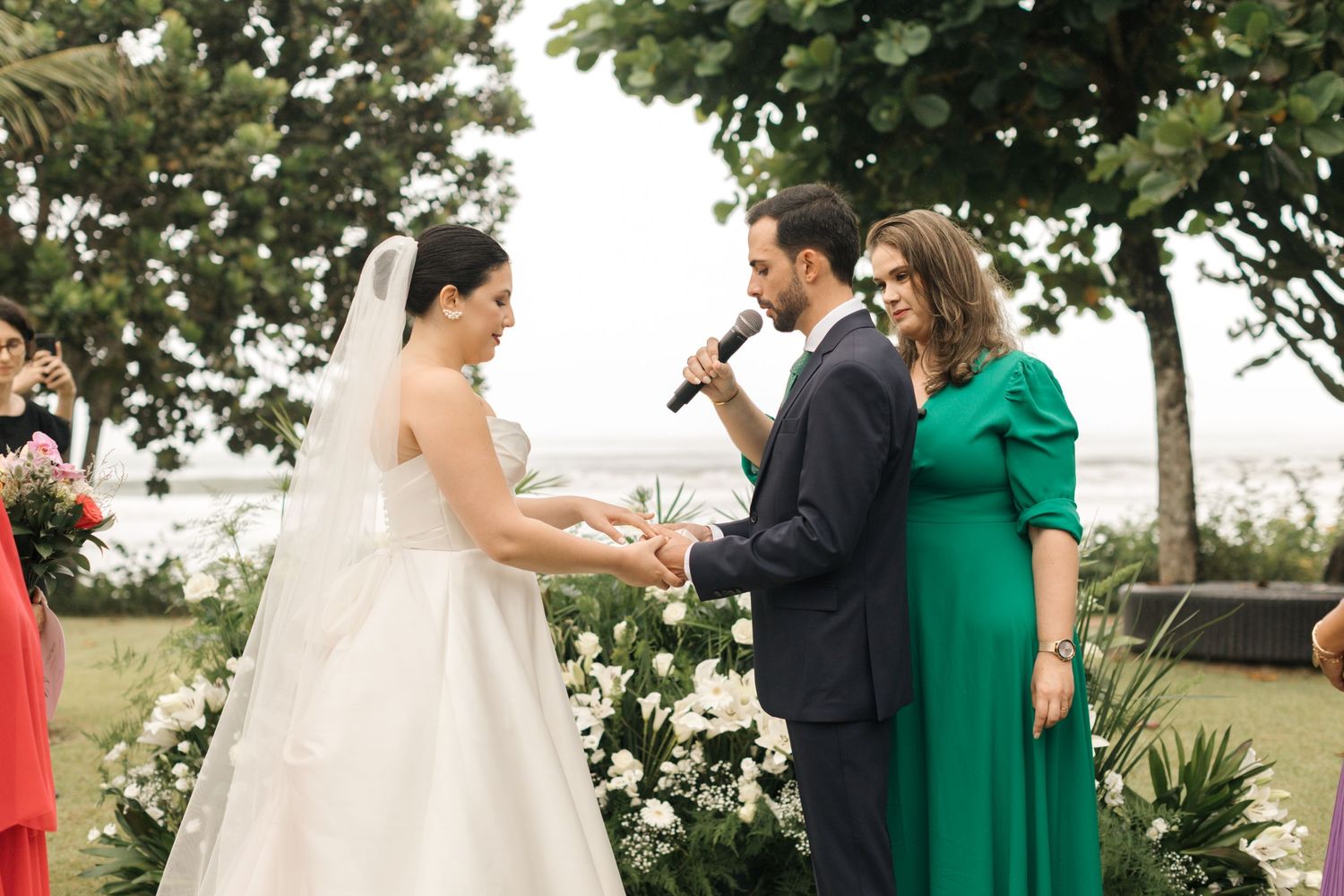 Outdoor wedding celebration with guests in emerald dresses and formal attire.