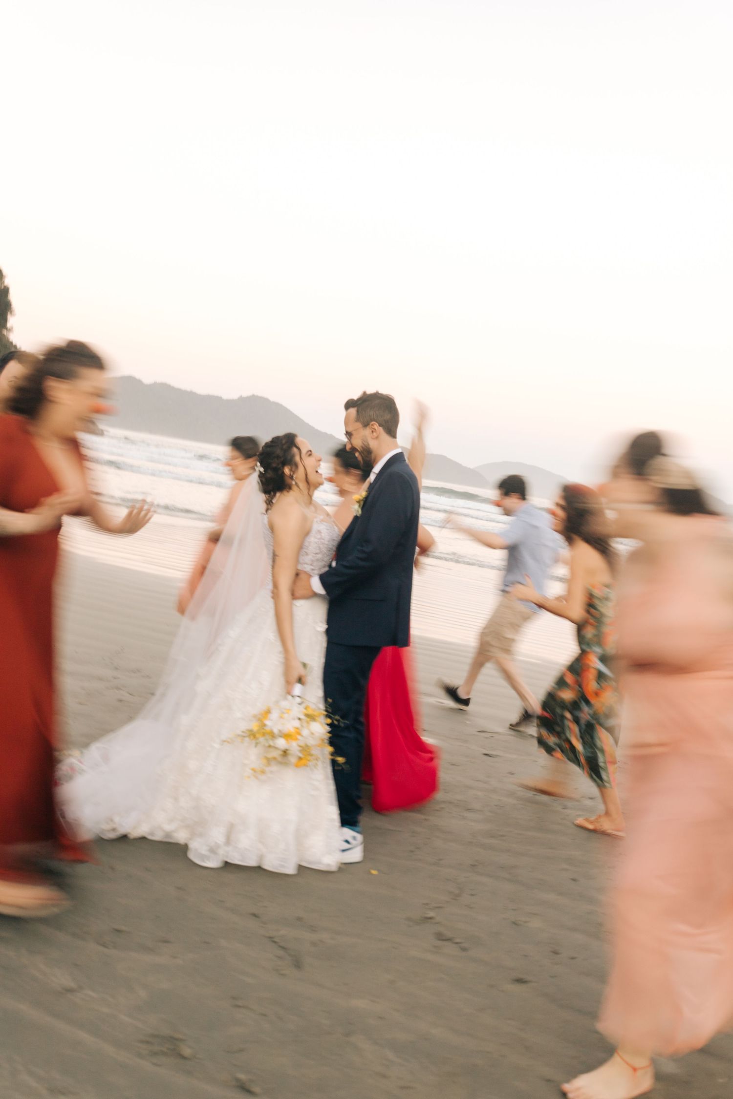 Candid wedding celebration moments captured on the beach with guests in colorful attire.