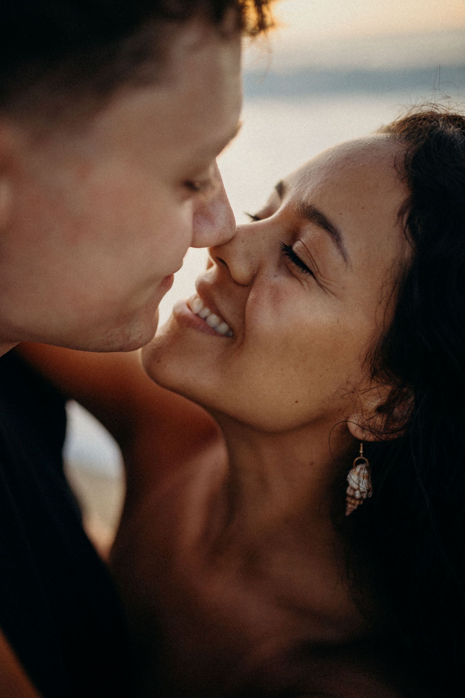 Intimate close-up of romantic moment captured in warm sunset lighting at the beach.