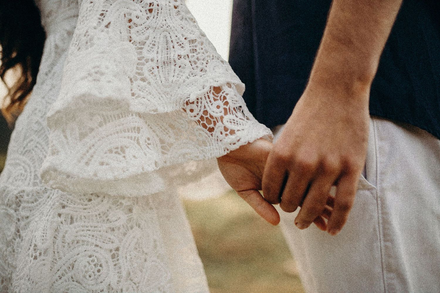 Close-up detail of hands holding each other during an outdoor photoshoot.