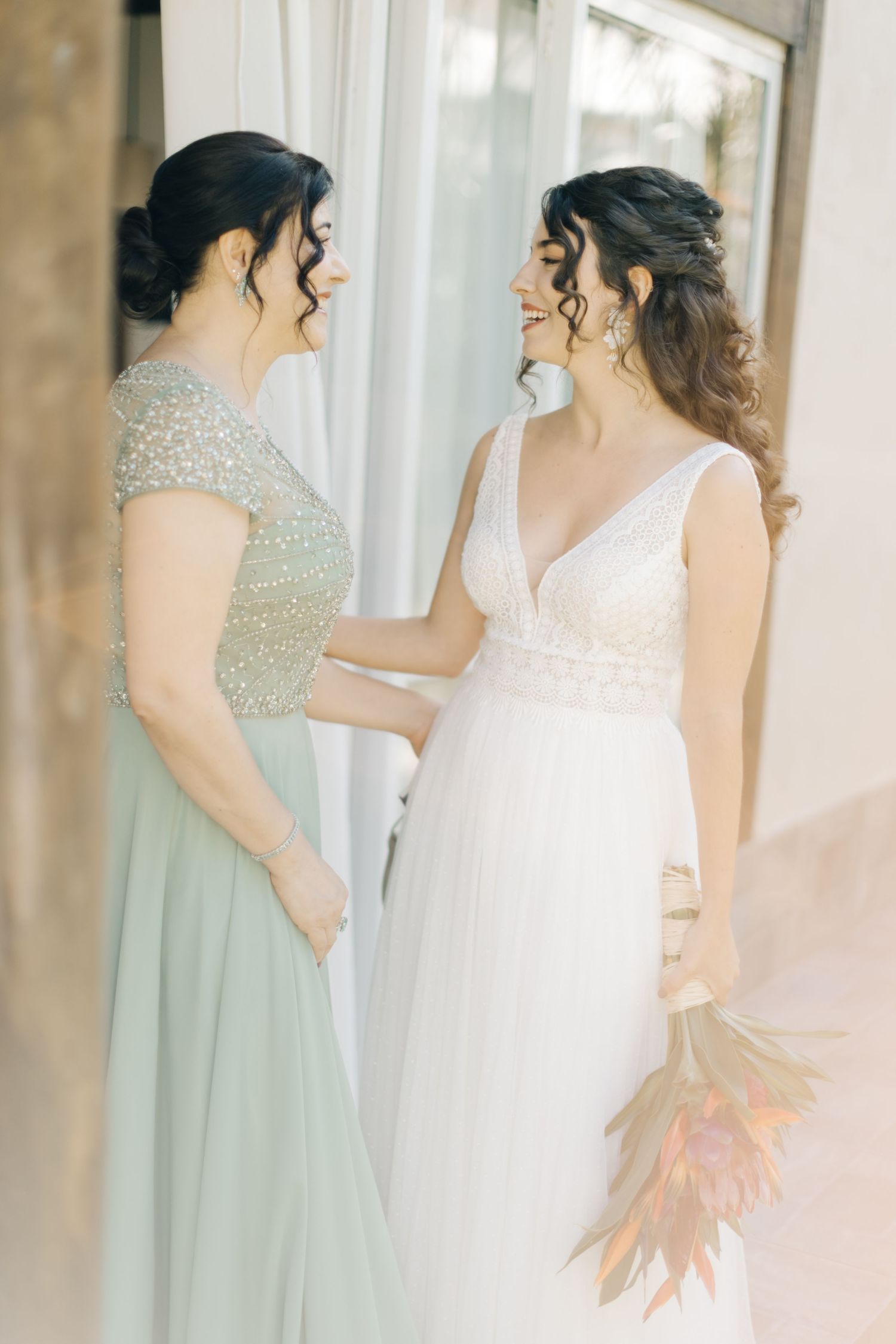 Bridesmaids in sage green dresses stand with bride in white gown.