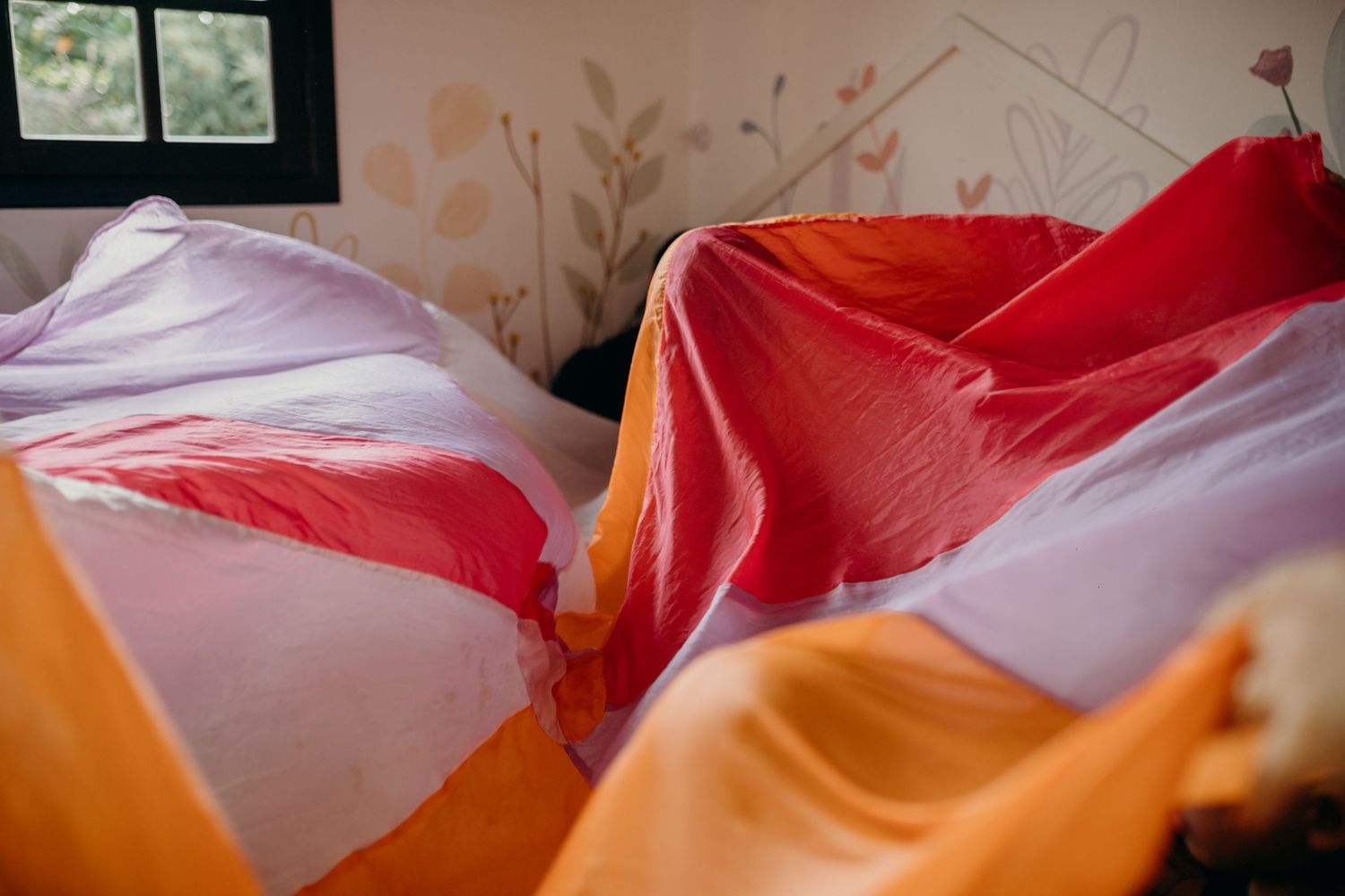 Vibrant red, orange and white fabric draped in flowing folds creating abstract shapes.
