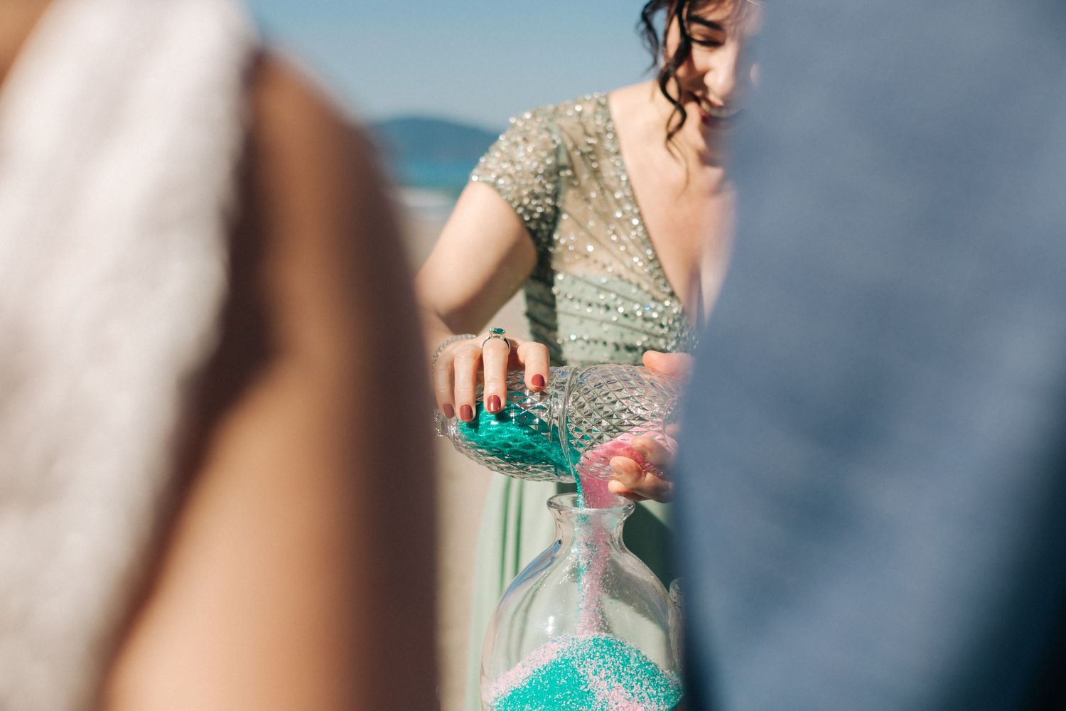 Someone pours bright turquoise liquid into elegant glassware at wedding reception.