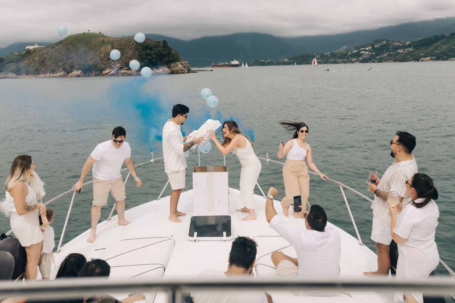 Guests in white clothing gather on a boat deck during a celebration with blue smoke effects.