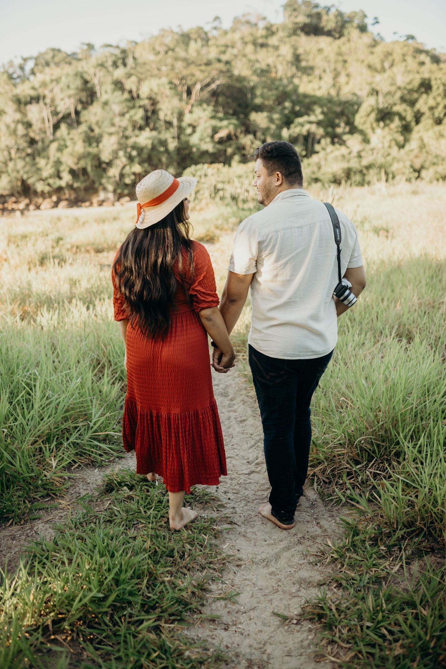 Couple walking hand in hand on nature trail with mountains in background.