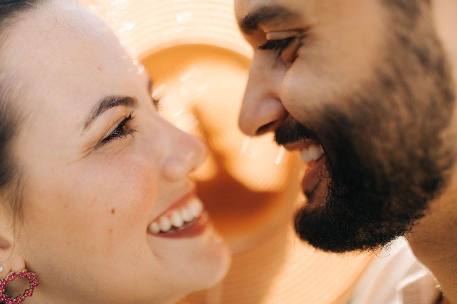 Sun-drenched portrait captures genuine laughter and intimacy between couple.
