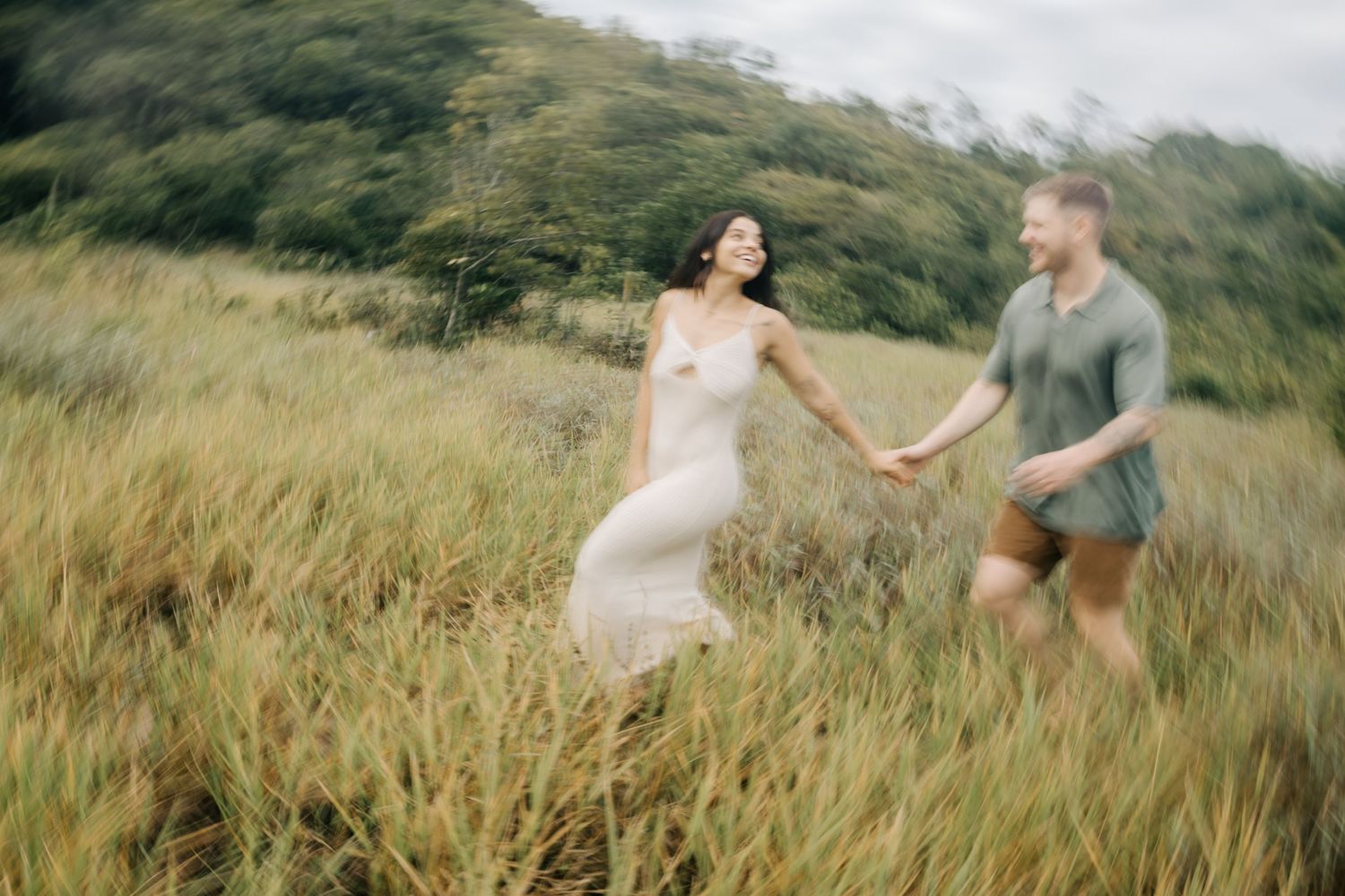 Intimate moments between a couple are captured against a backdrop of mountains and tall grass.