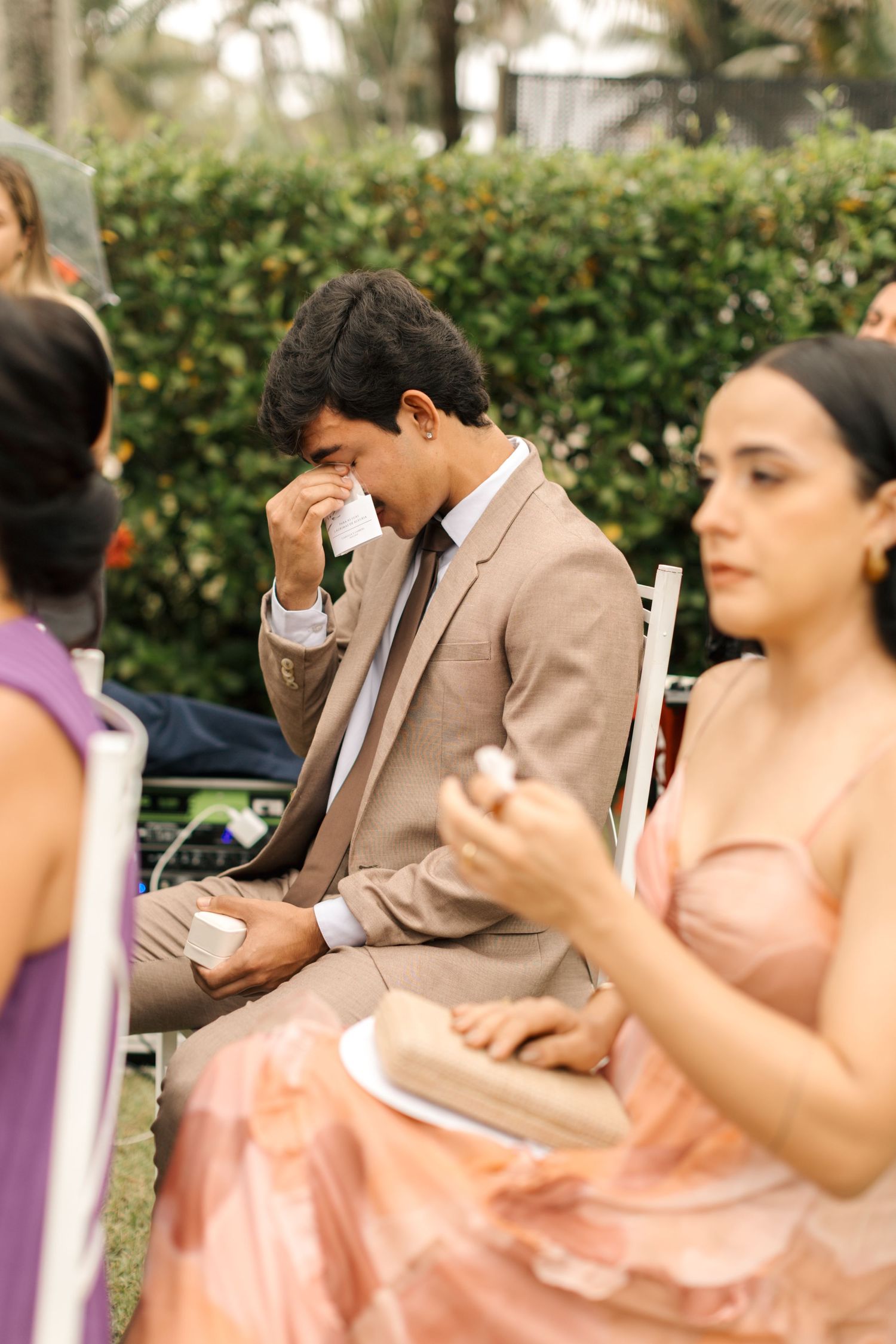 Emotional wedding guests wipe tears during a touching outdoor ceremony moment.