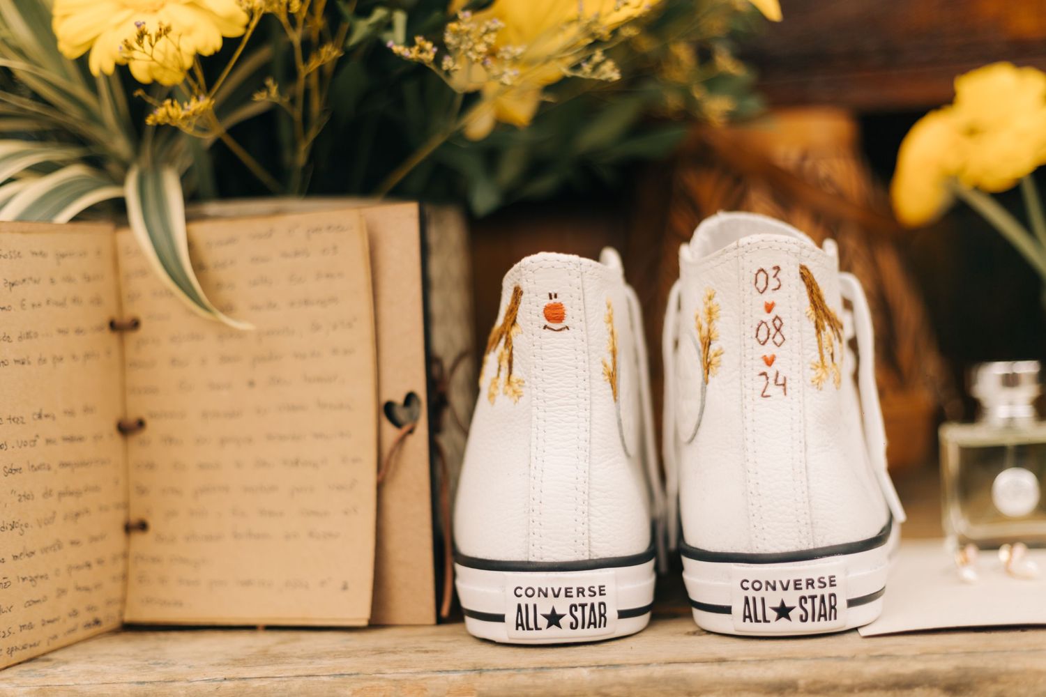 White Converse sneakers with gold details arranged as wedding accessories.