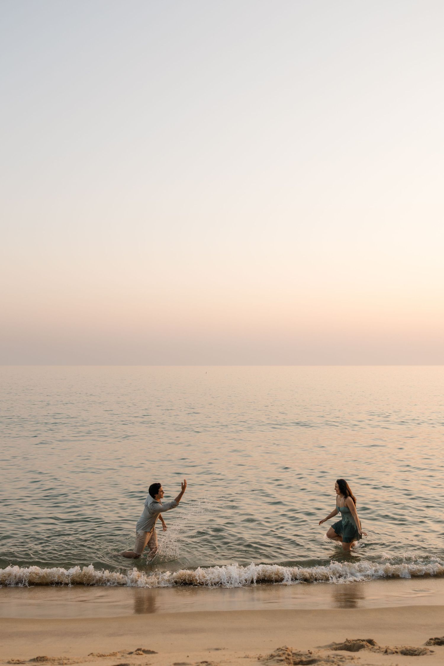 Joyful silhouettes splashing and playing in the ocean waves during golden hour at the beach.