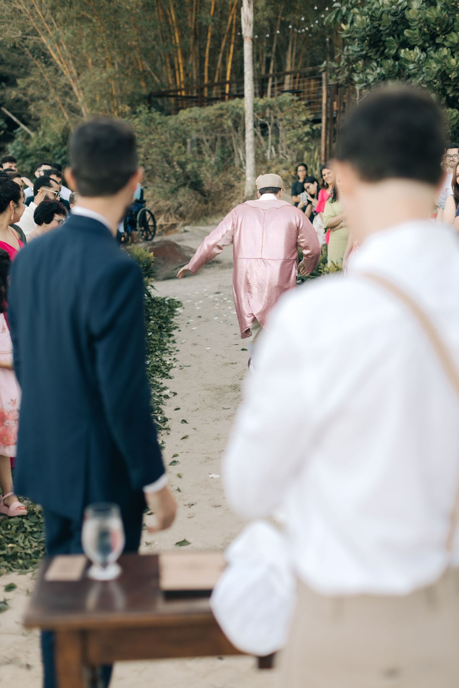 Person in pink jacket walks away on garden path during outdoor event.
