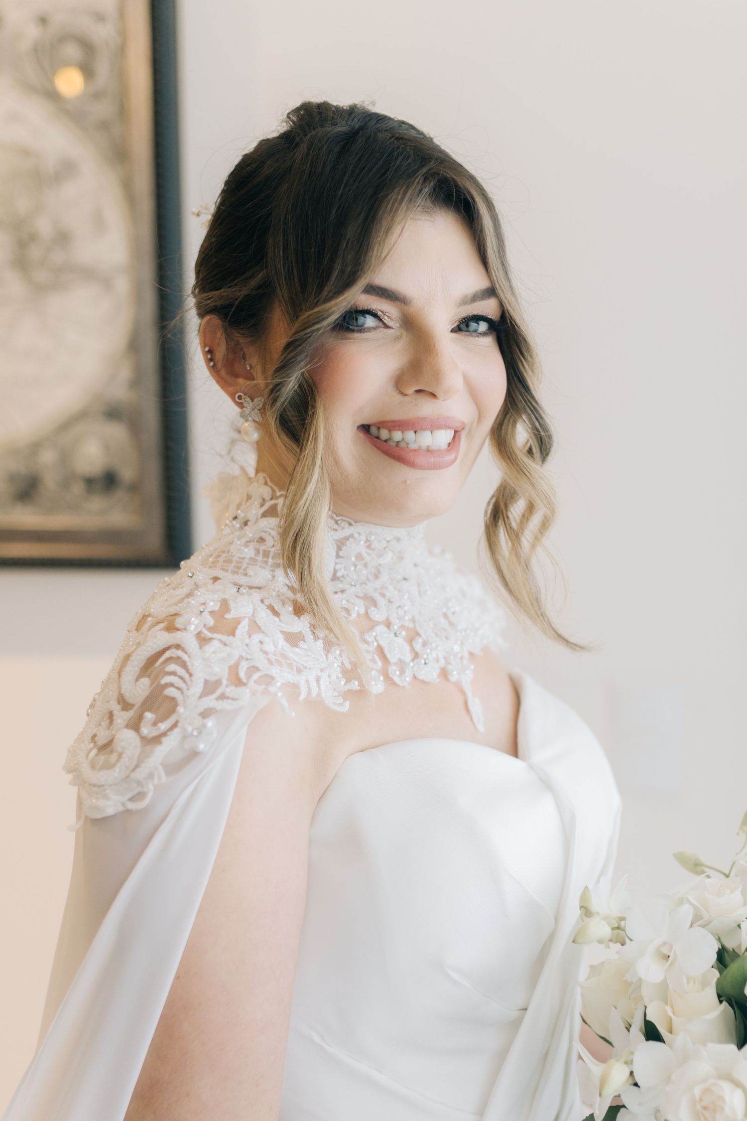 Wedding gown details featuring delicate lace high neckline and romantic upswept hairstyle.