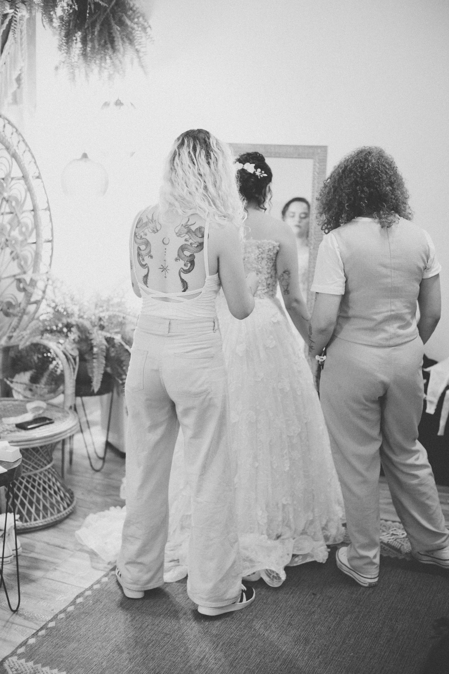 Wedding party members in light colored outfits gathered around bride in white dress.