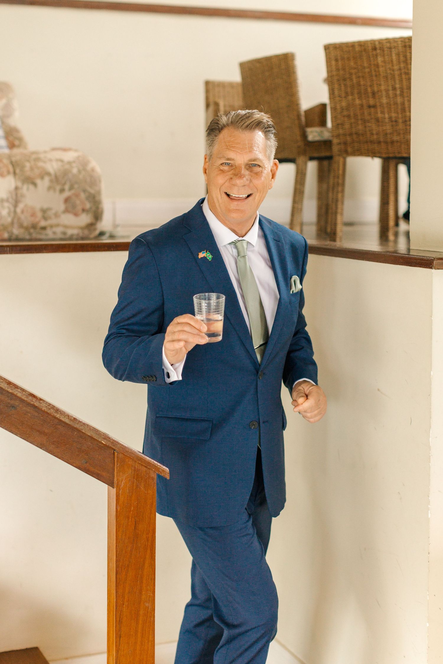 A person in a navy blue suit and tie gestures expressively during a wedding celebration.