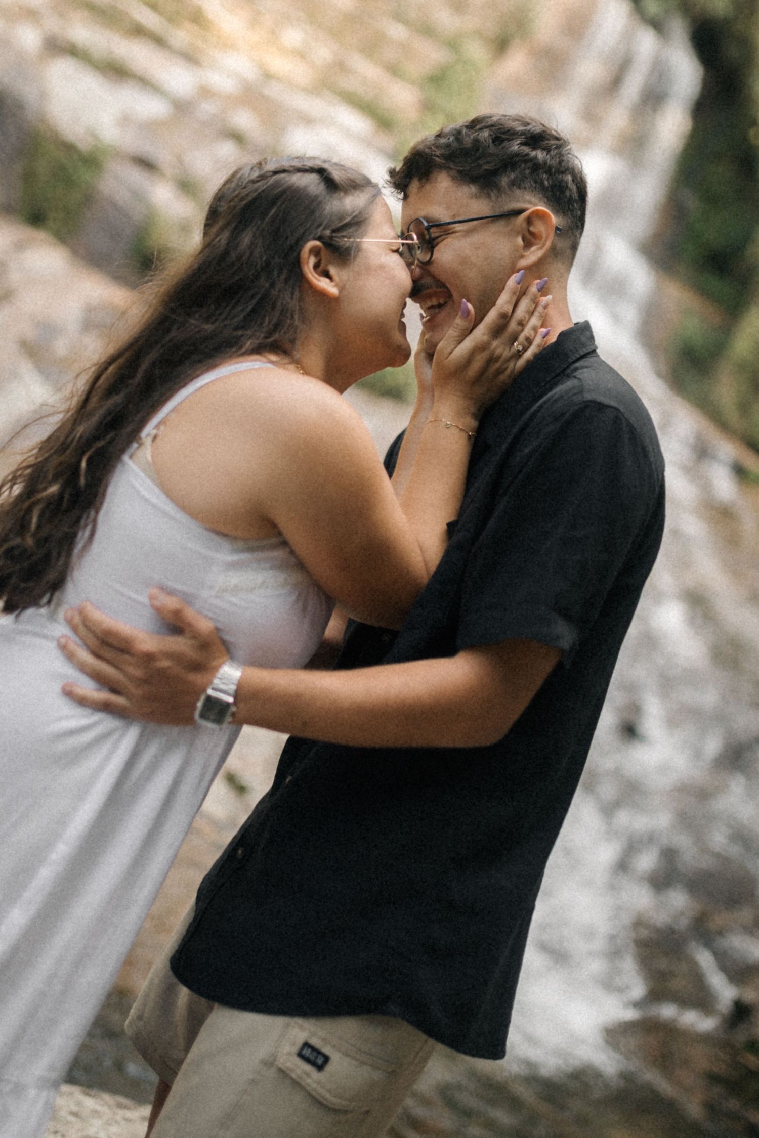 A romantic couple embraces tenderly in front of a waterfall backdrop in a sequential photo series.