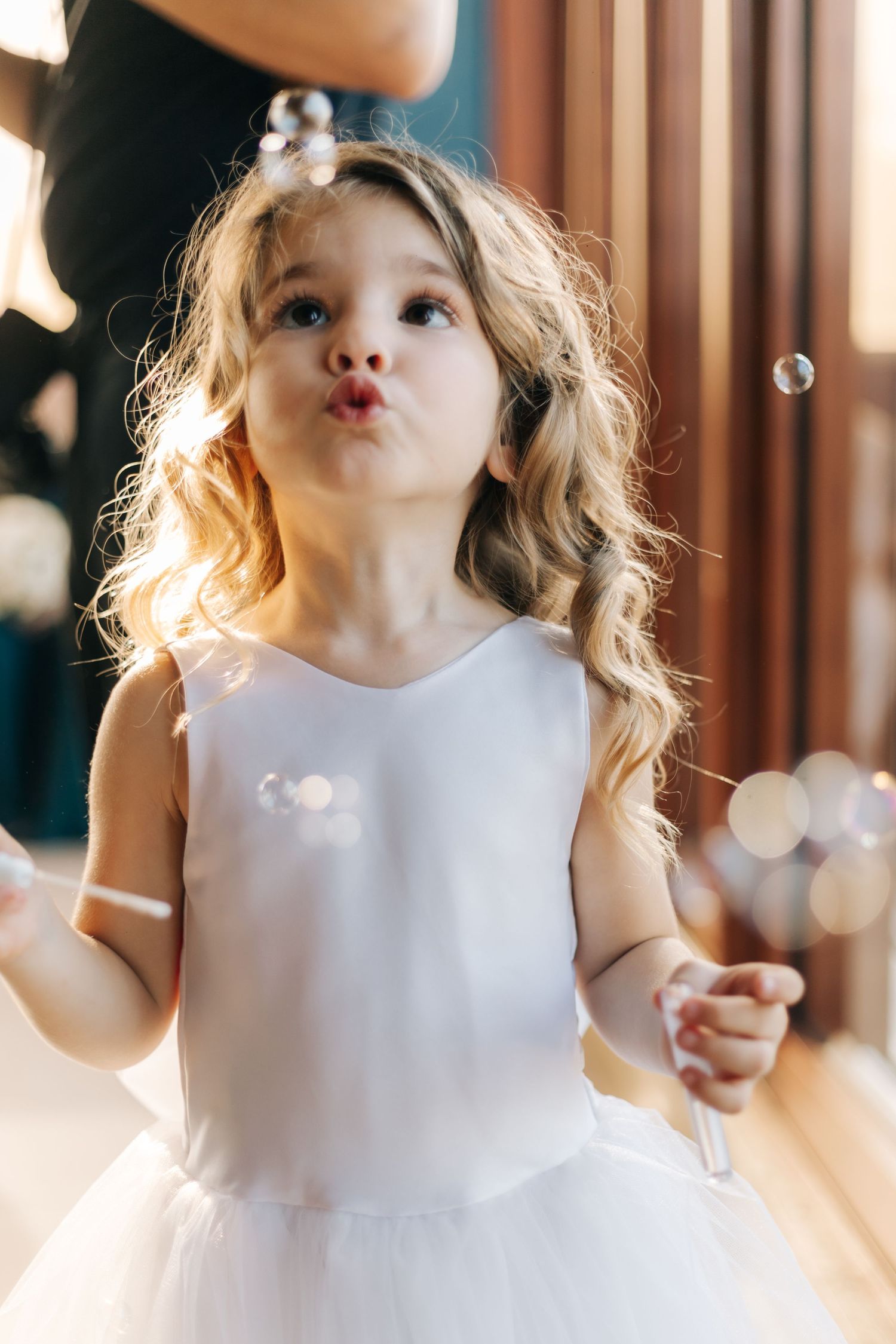 Playful moment with bubbles and white dress at wedding celebration.