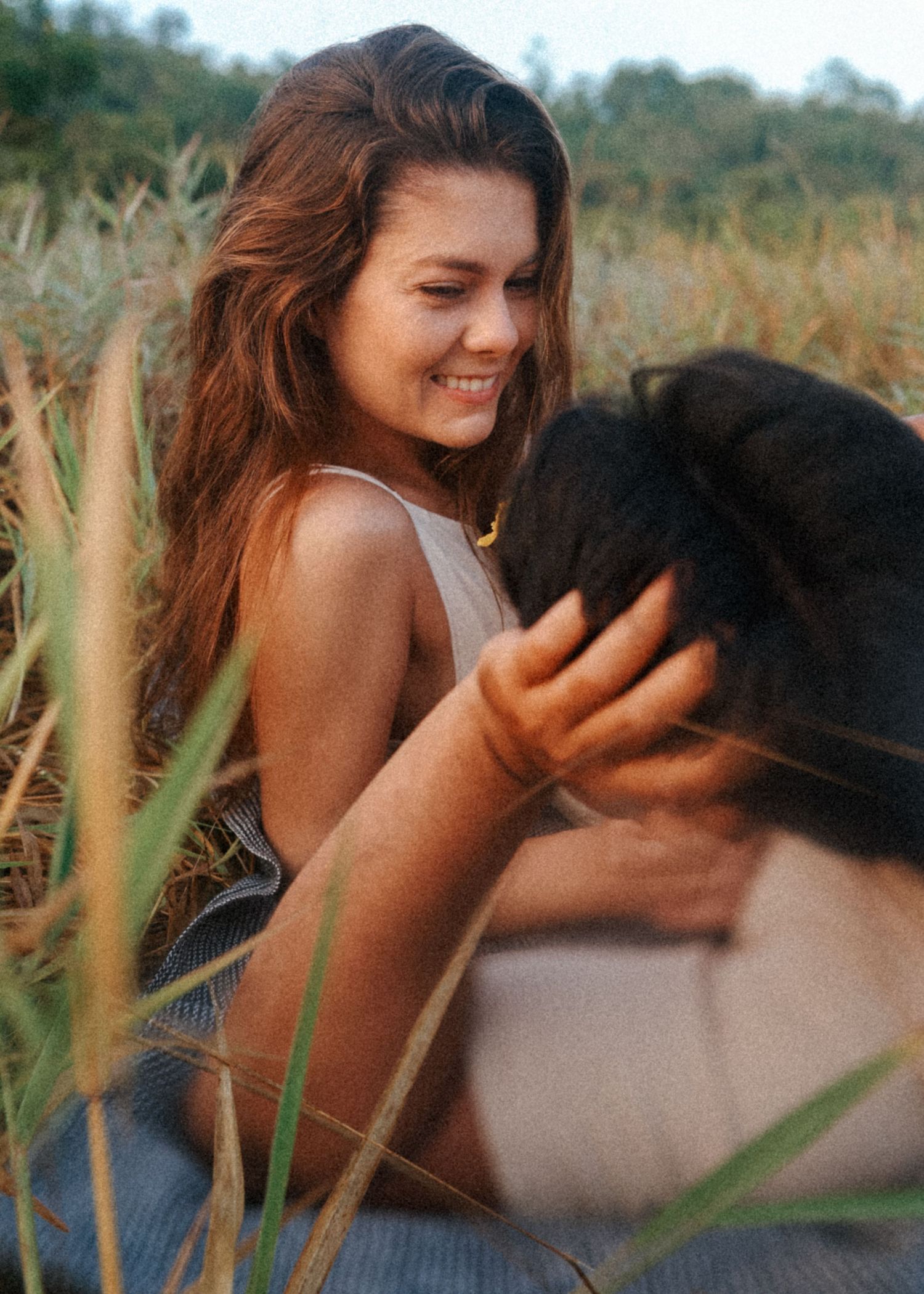 Romantic couple sharing tender moments among tall grass on a sunny day.