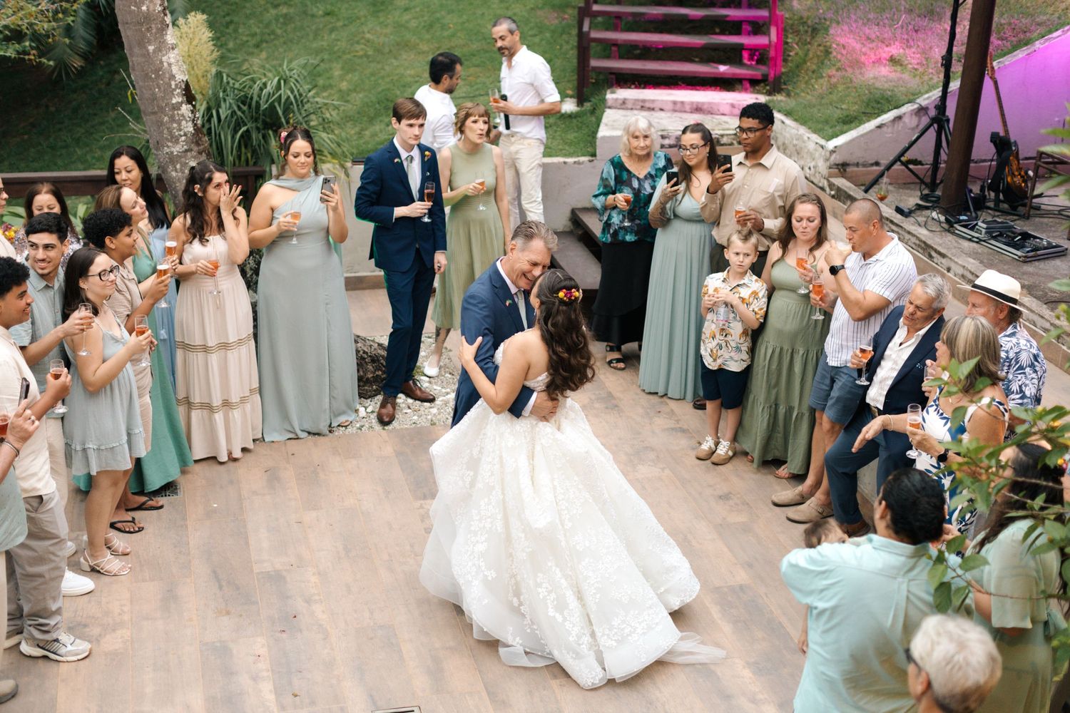 Wedding guests line up on both sides of an outdoor path to celebrate during a tropical destination ceremony.