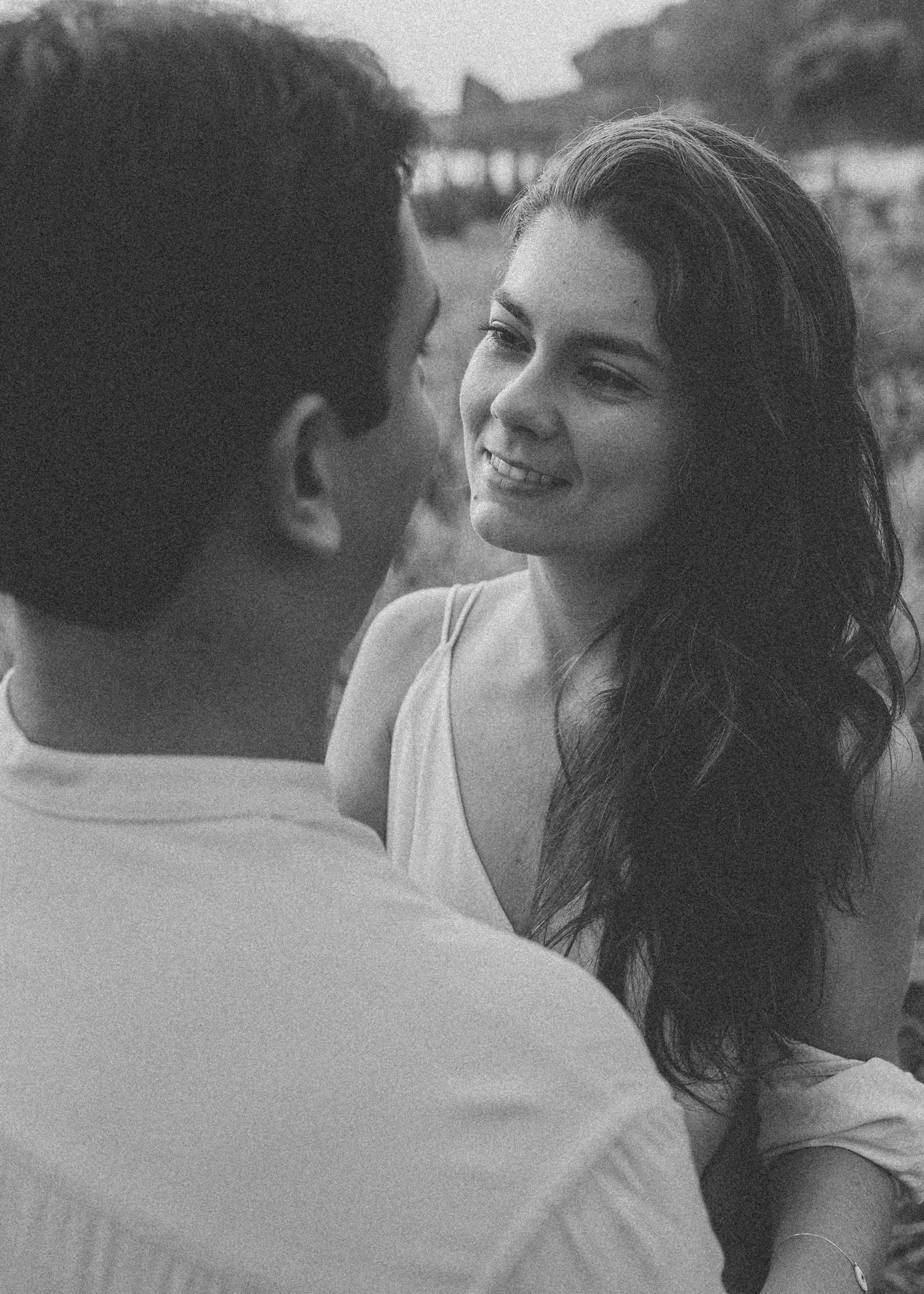 A black and white portrait of a couple sharing joyful moments outdoors.