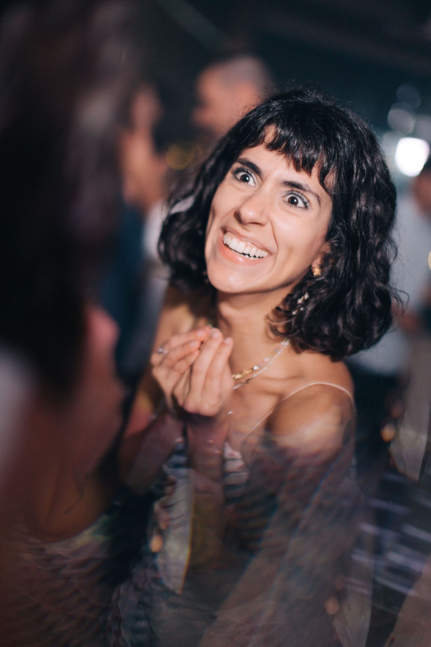 Partygoer smiles while enjoying the wedding celebration with candid lighting.