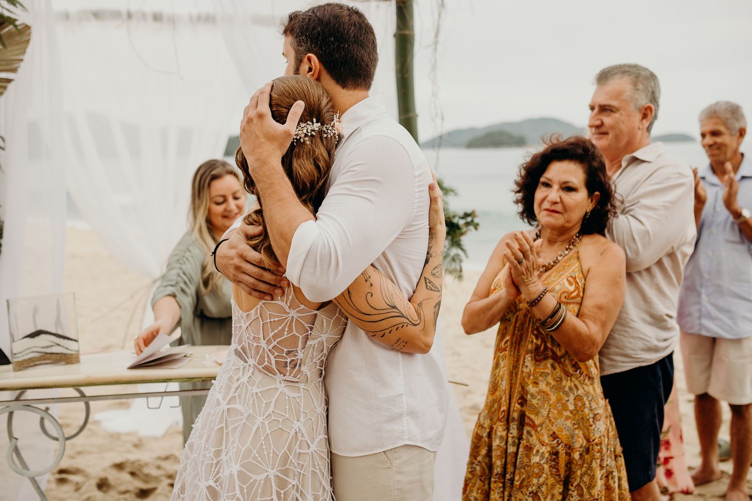 Wedding ceremony participants share emotional moments during outdoor beach celebration.
