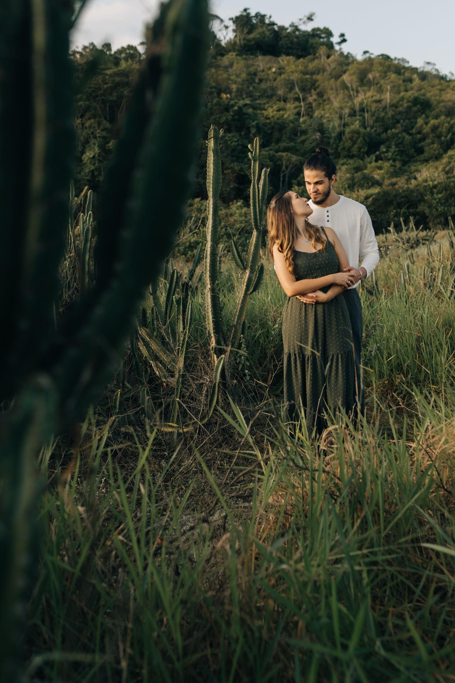 Romantic photoshoot in a field of tall grass with mountains in the background.