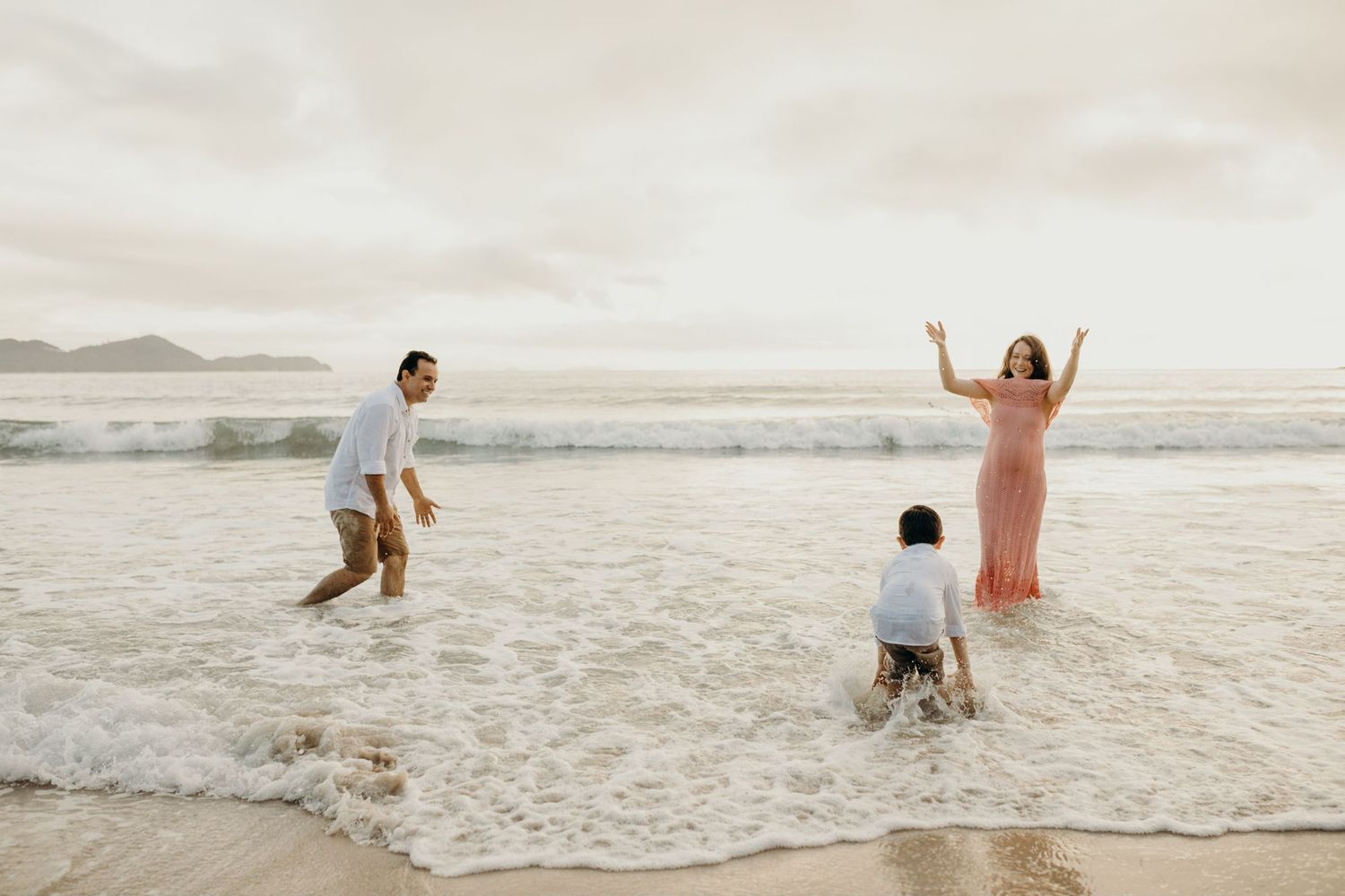 People jumping and playing in the ocean waves at sunset on a beautiful beach.