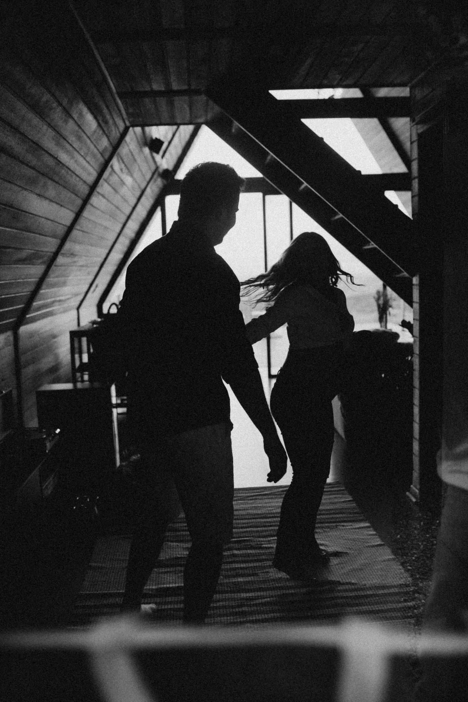 Dancing silhouettes move playfully in an attic space with streaming light from above.