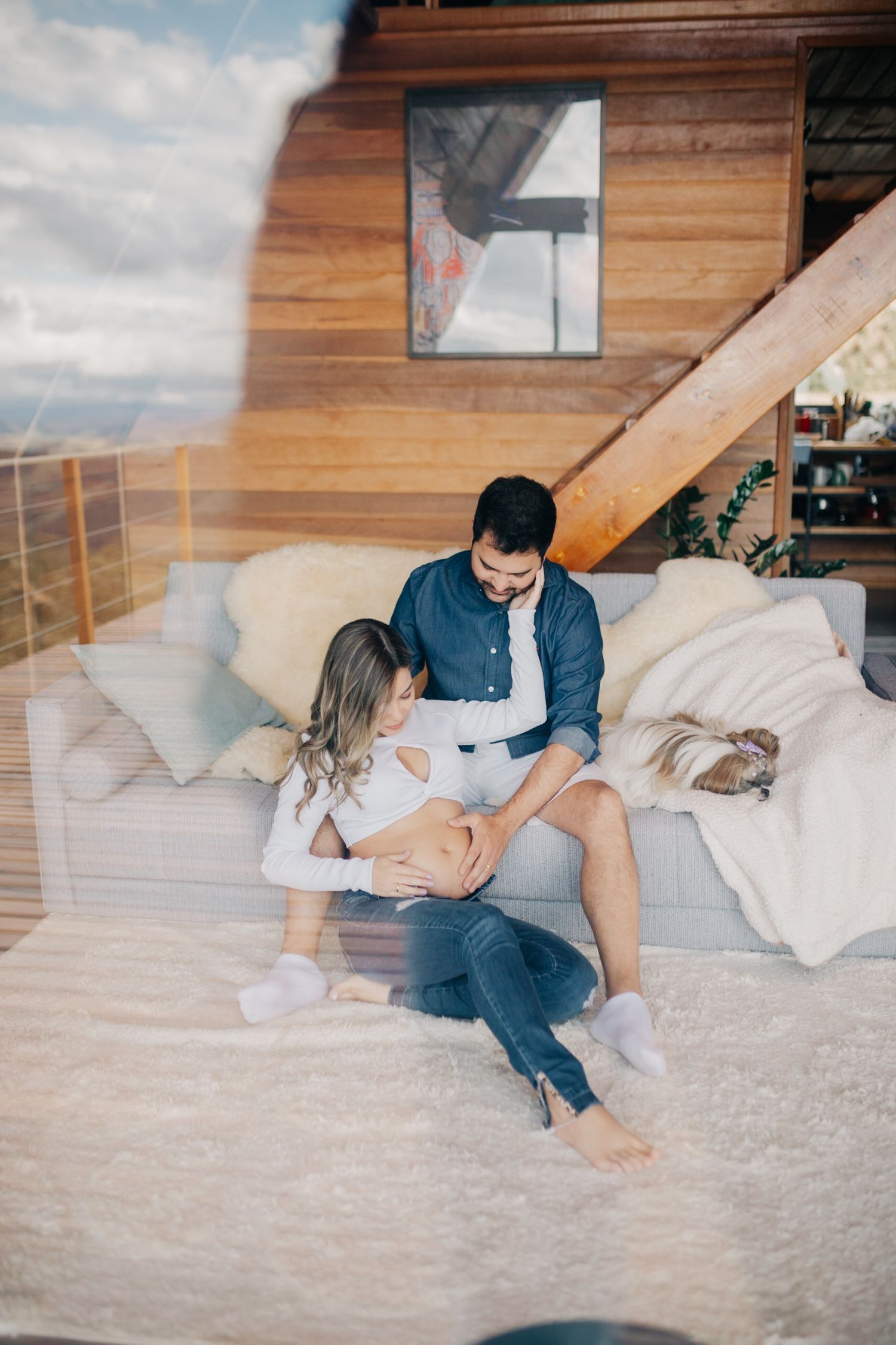 Couple relaxing on plush white bedding in a modern wooden cabin setting.