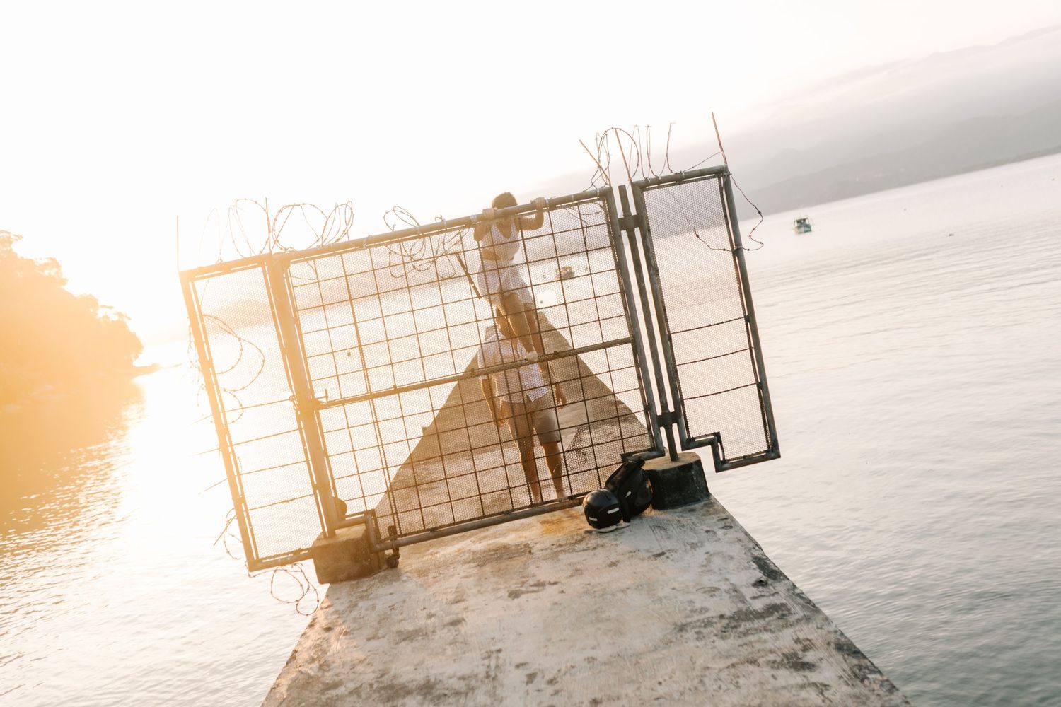 Silhouette of a fence against a golden sunset over the ocean.