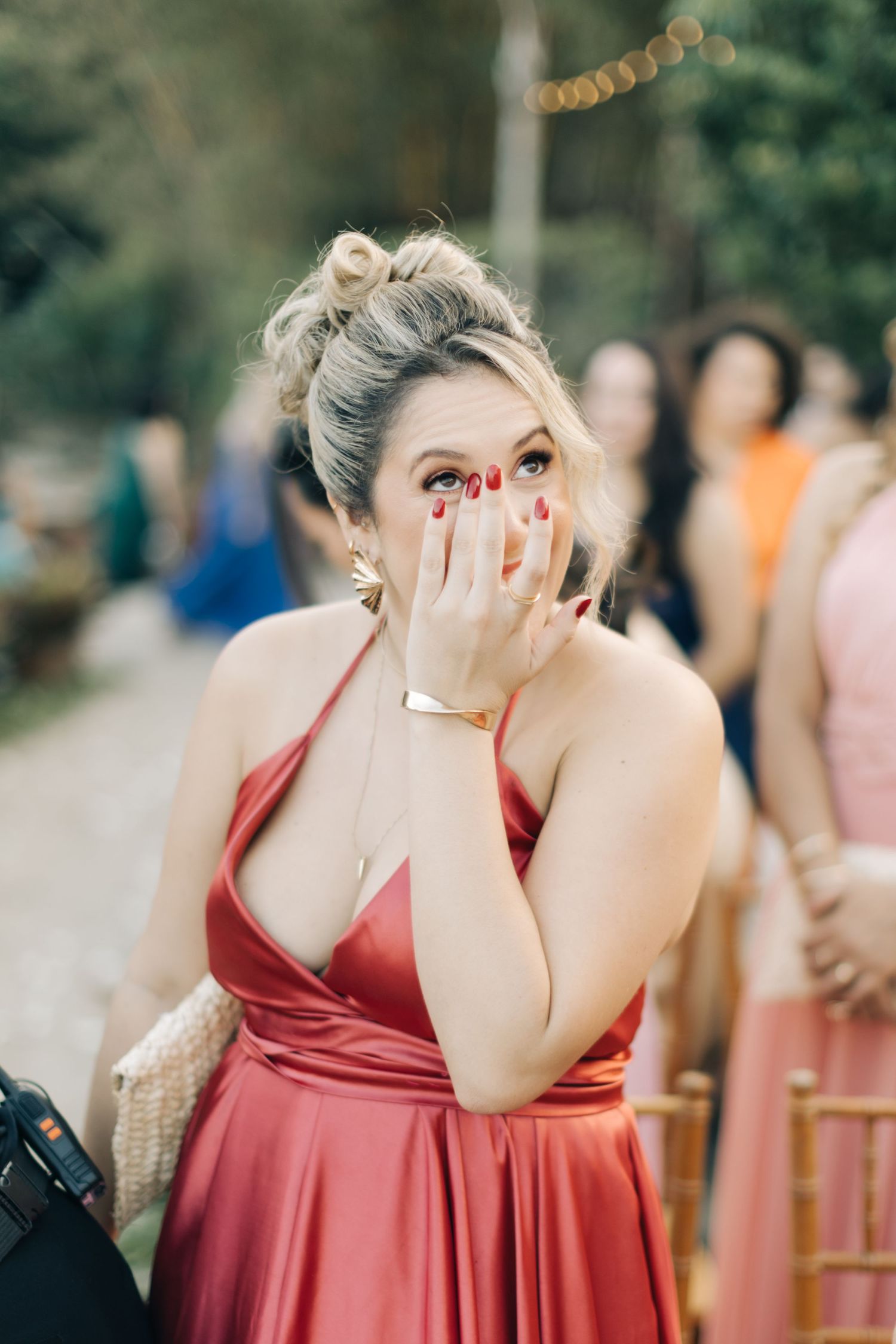 Wedding guest in red satin dress shows surprised expression during ceremony.