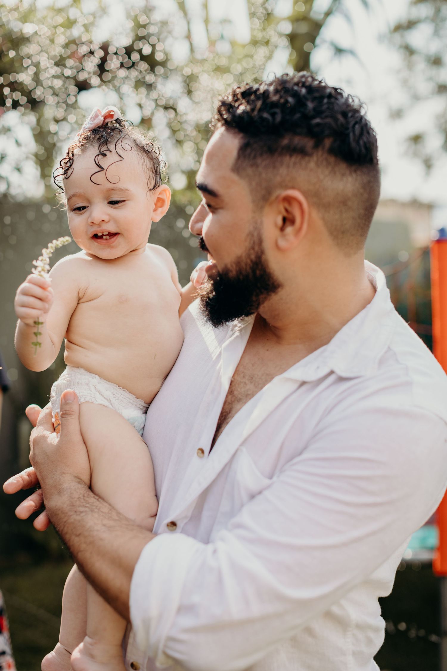 A tender moment between parent and baby outdoors in natural sunlight.
