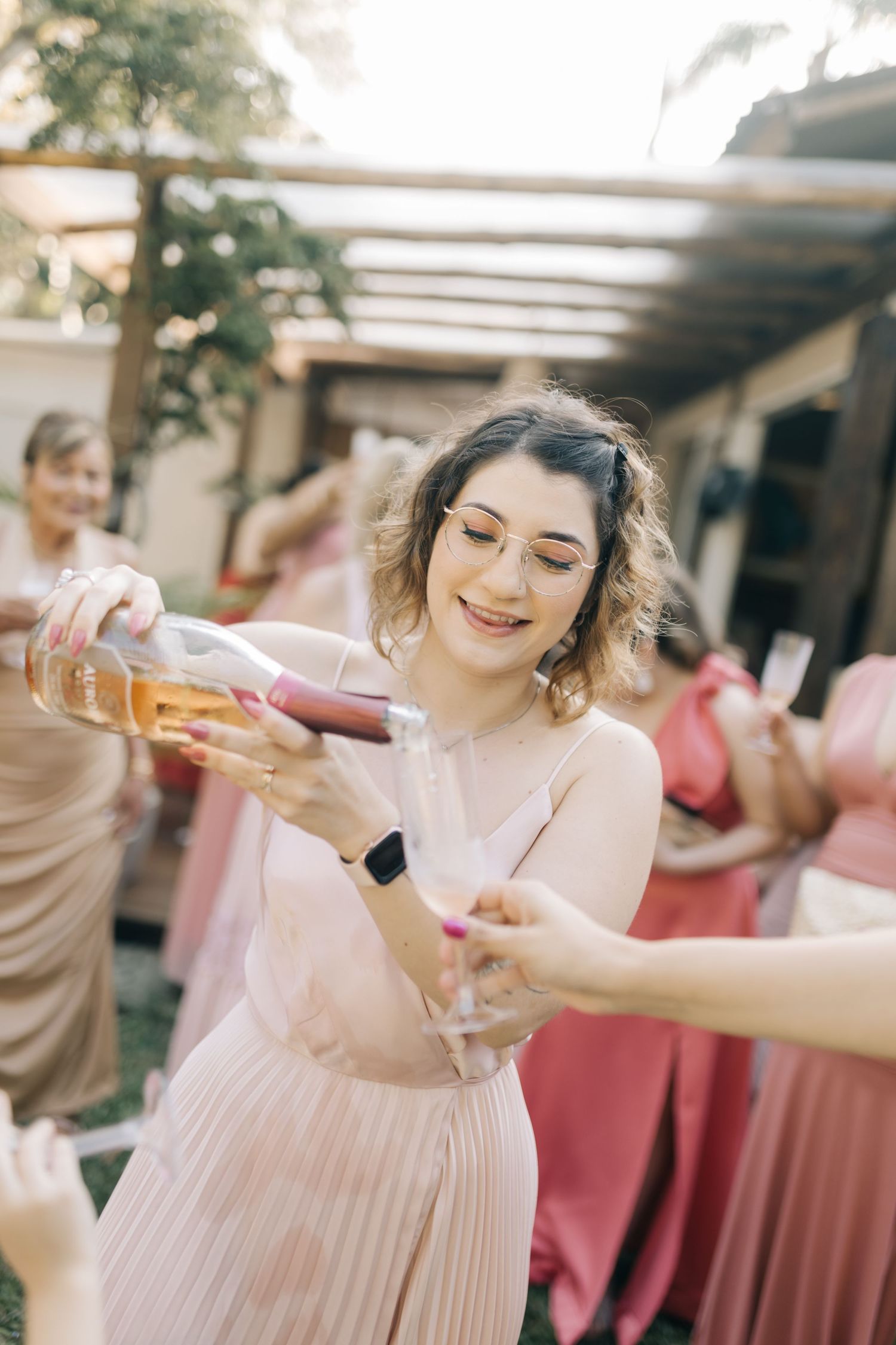 Wedding party in blush pink dresses toasting with champagne at a celebration.