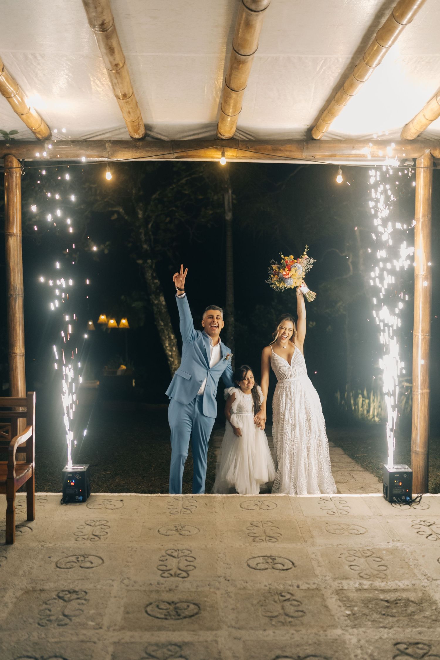 Wedding celebration on a covered patio with sparklers and string lights creating a magical nighttime atmosphere.