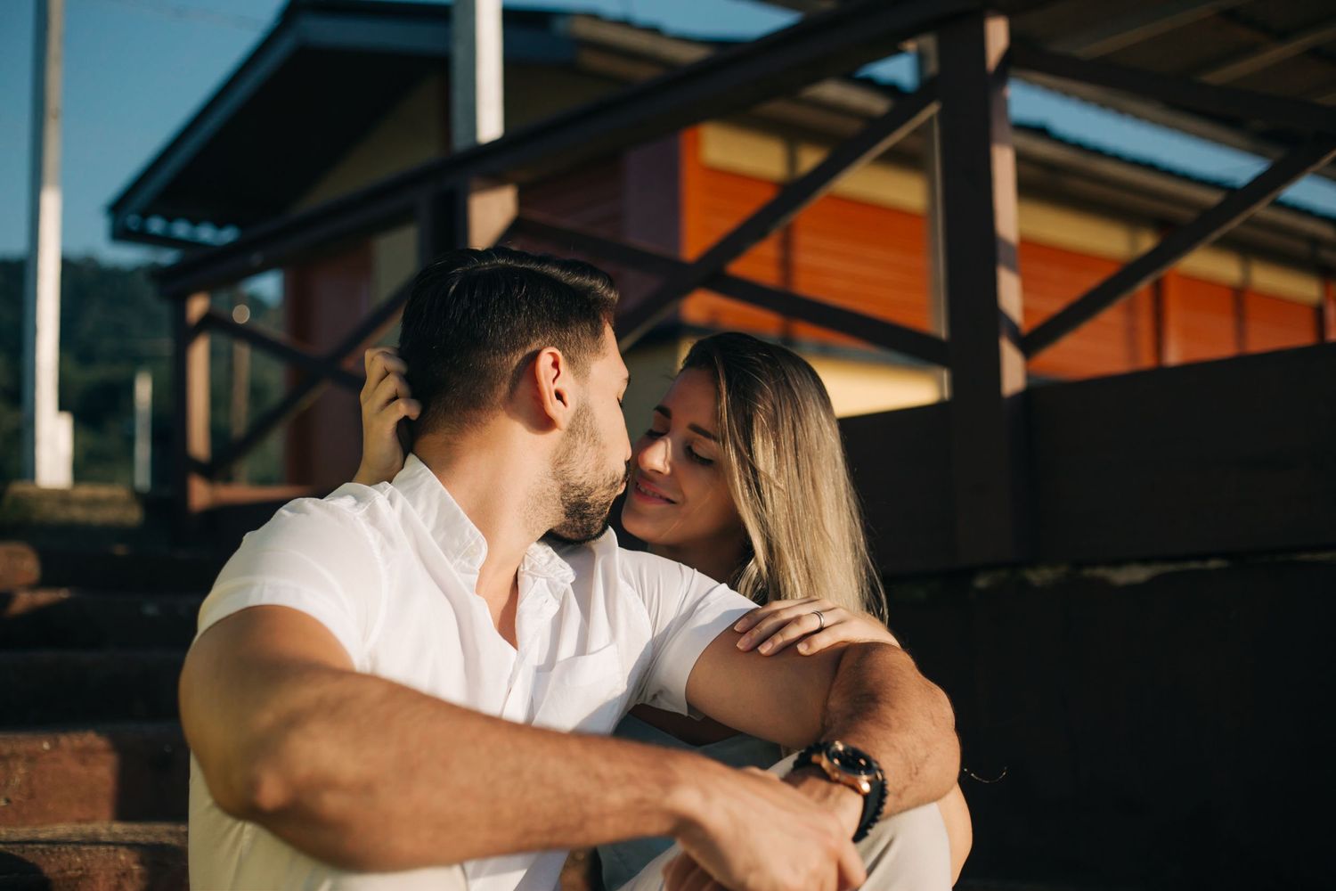 Couple in white and casual wear sharing affectionate moment on industrial steps.