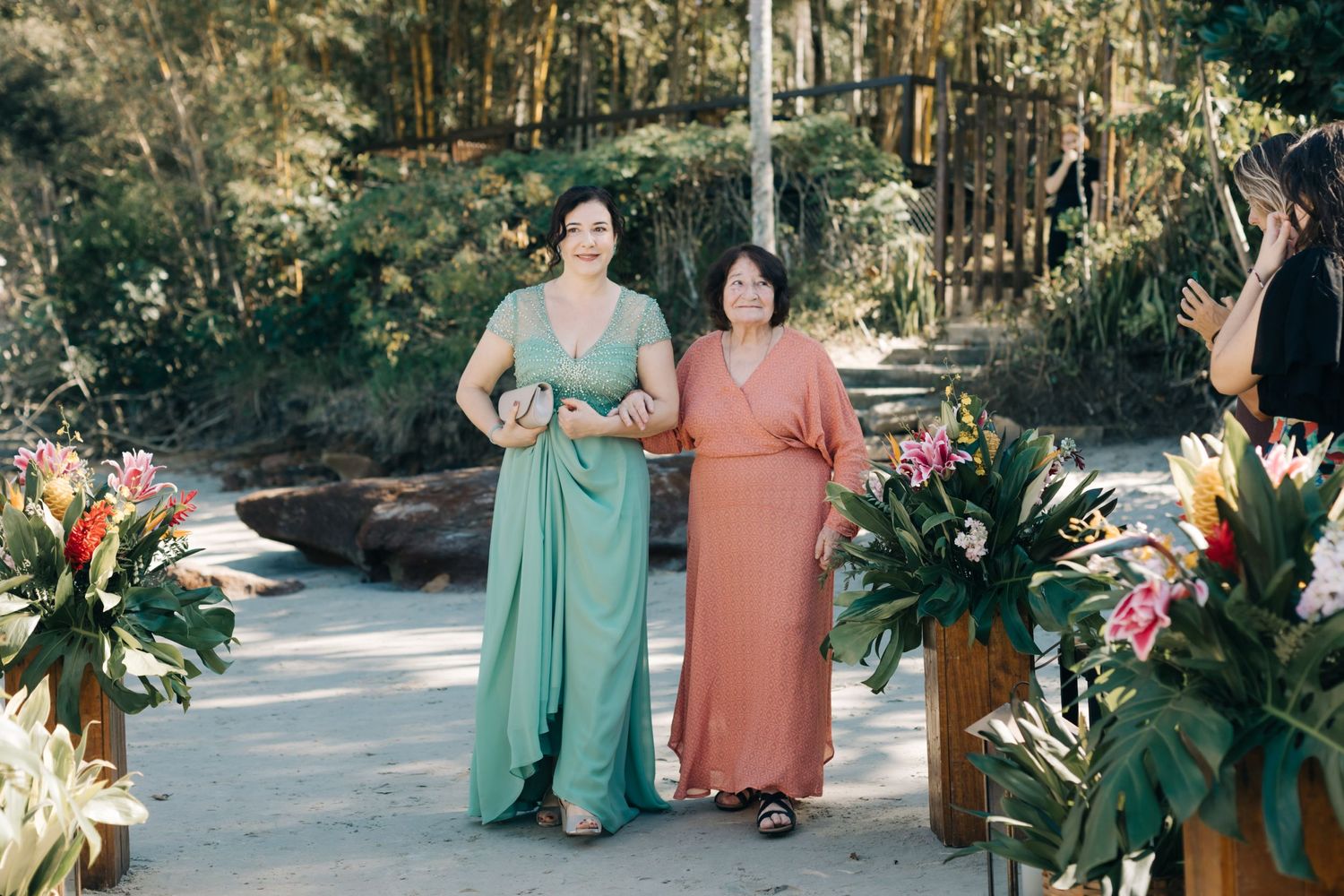 Wedding party members in mint green and coral dresses gathering outdoors.