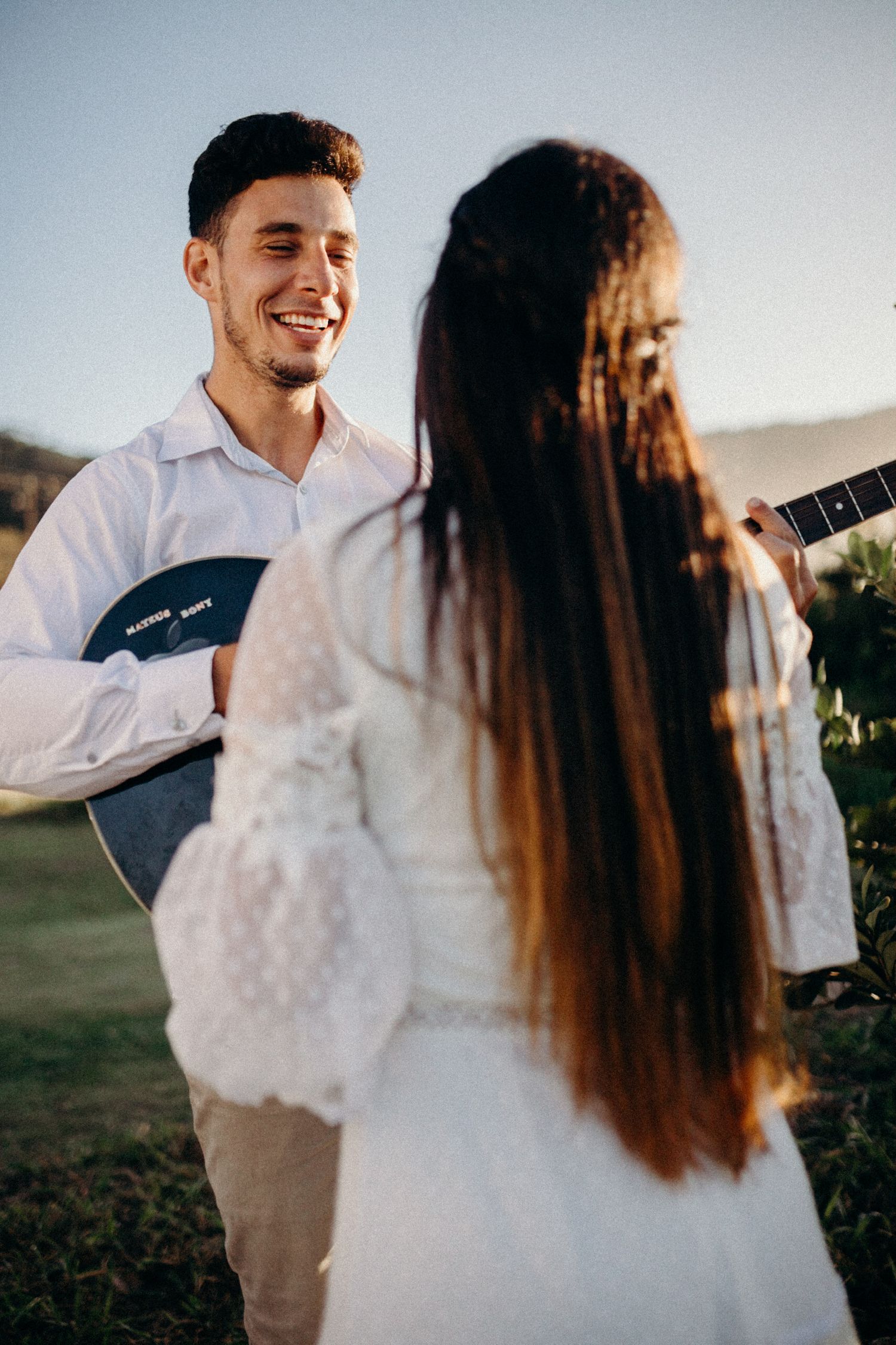 Couple shares musical moment during outdoor coastal photoshoot.