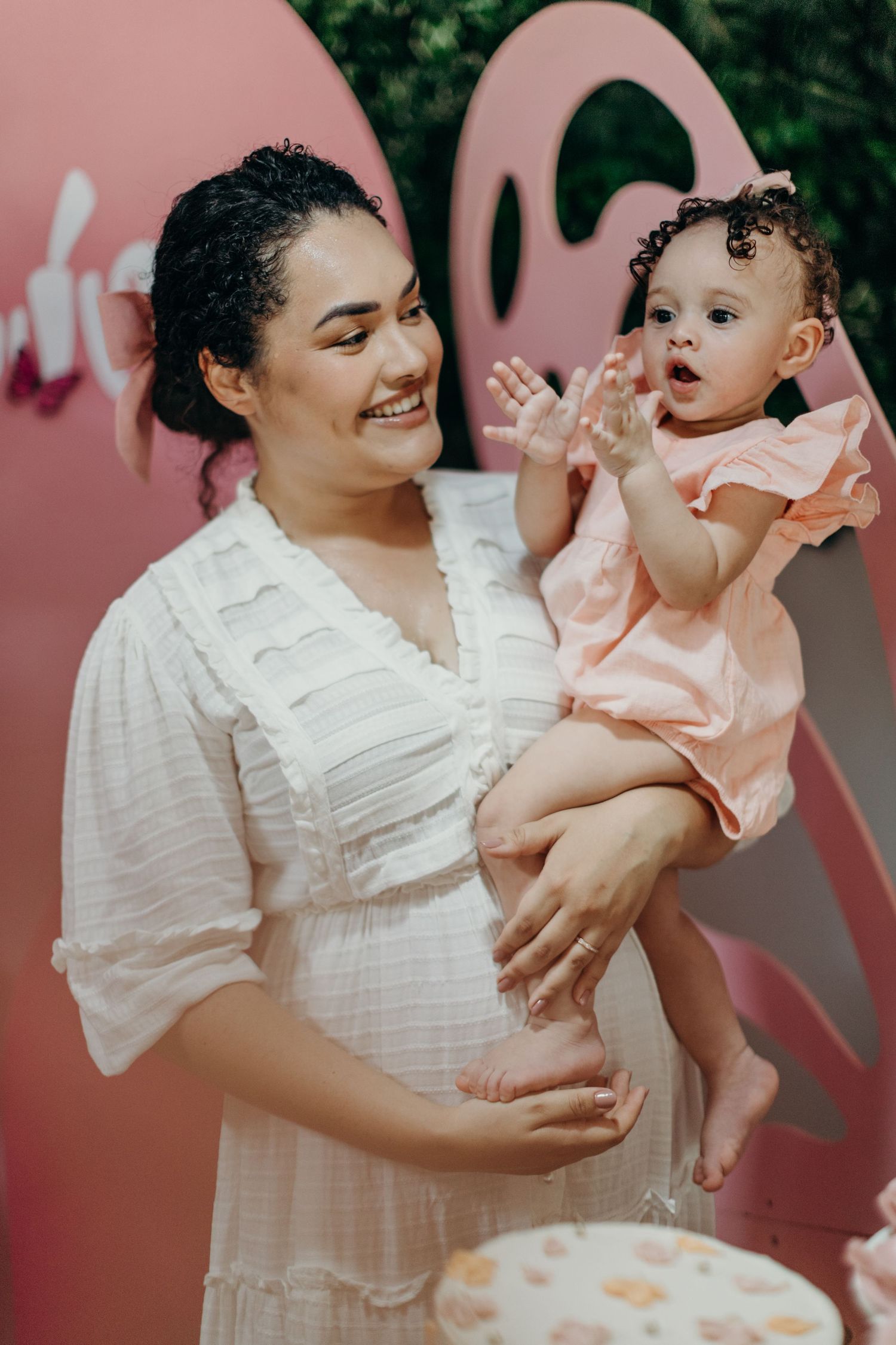 Sweet celebration moments captured against a pink backdrop with festive decorations.