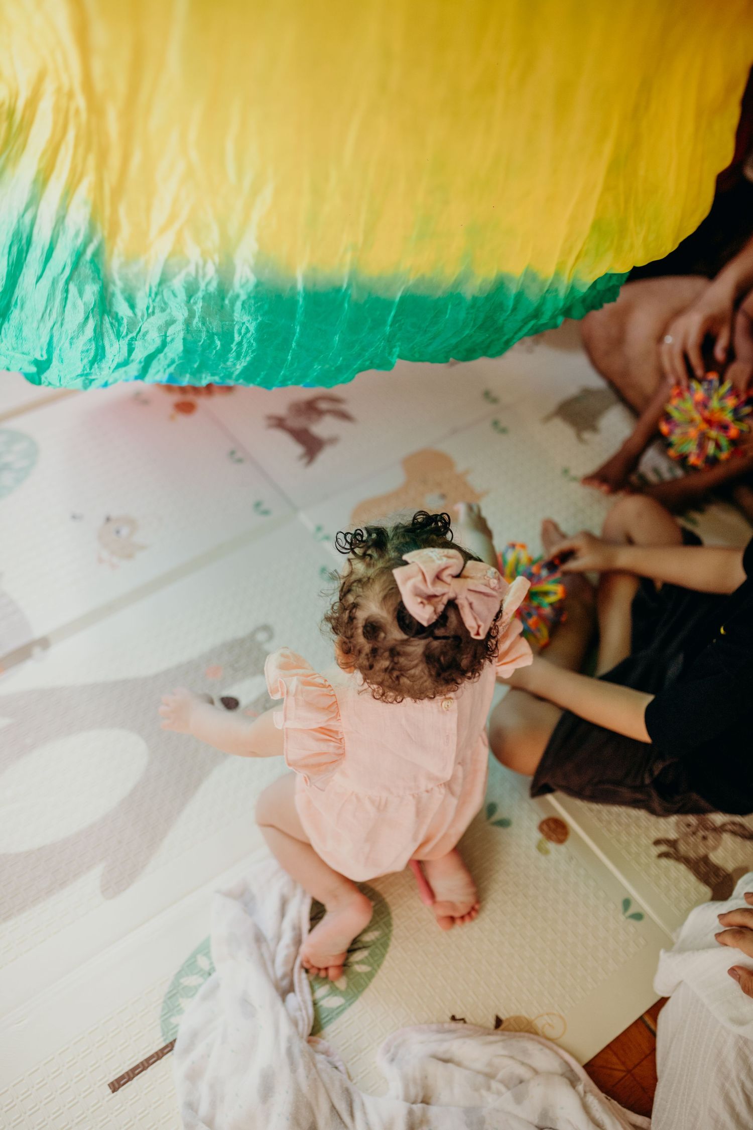 Colorful fabric sheets in yellow and turquoise drape over a play area with floral decorative elements.