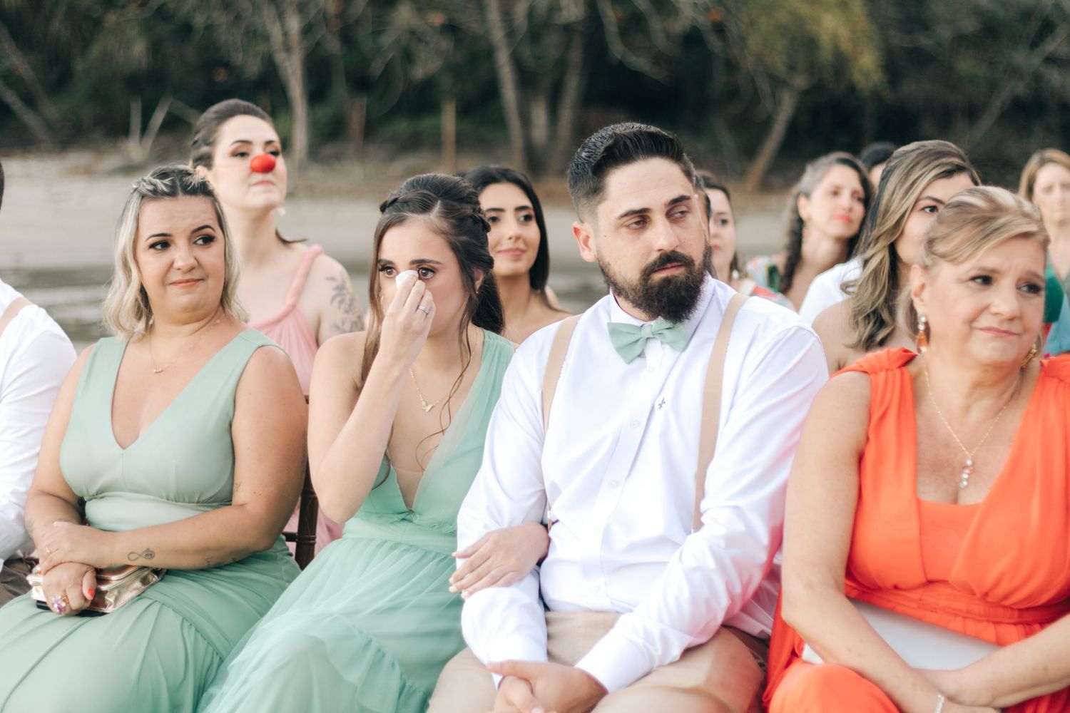 Wedding party members in pastel dresses react emotionally during ceremony.