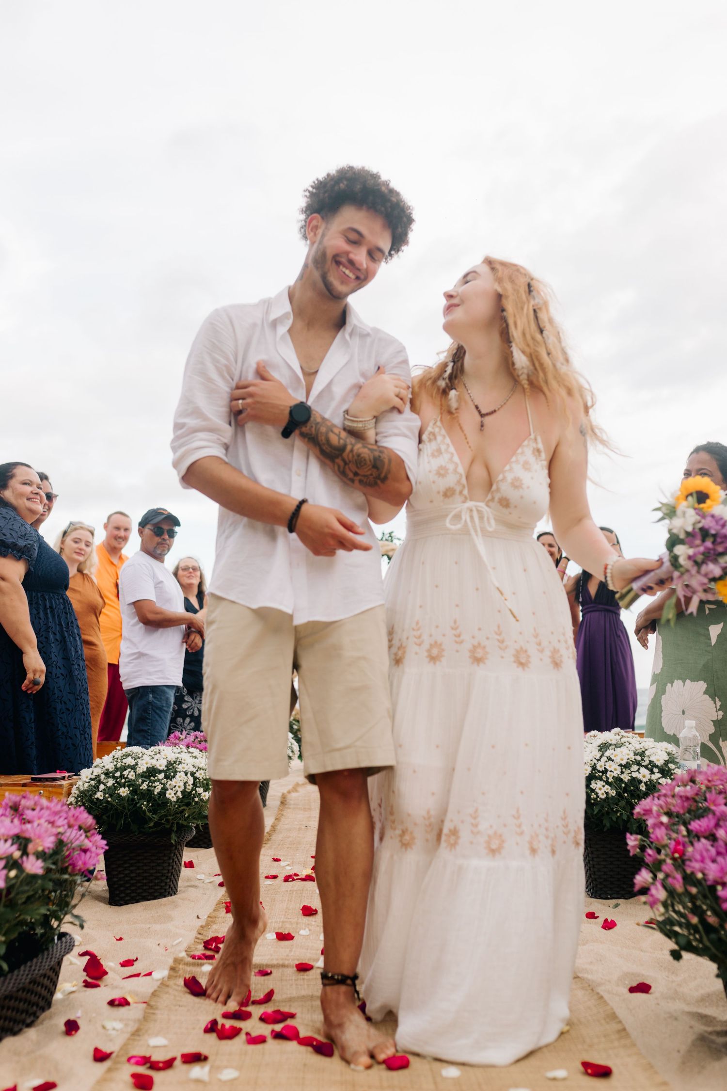 A couple shares a happy moment with their small dog during their beach wedding ceremony.