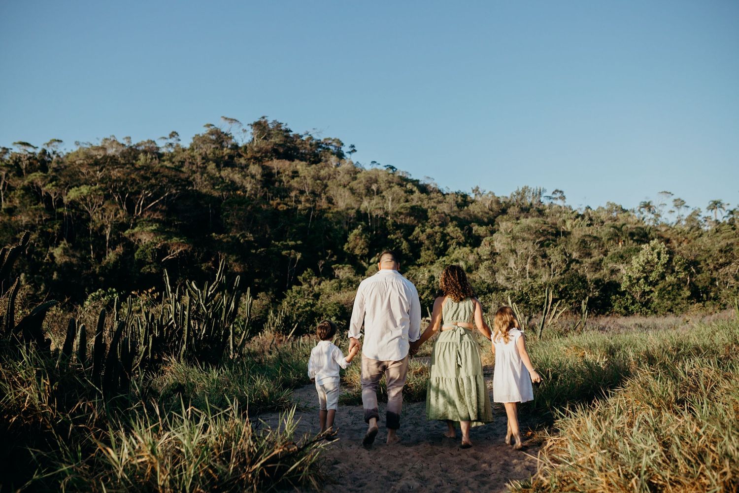 A family walking together on a trail with mountains and blue sky in the background.