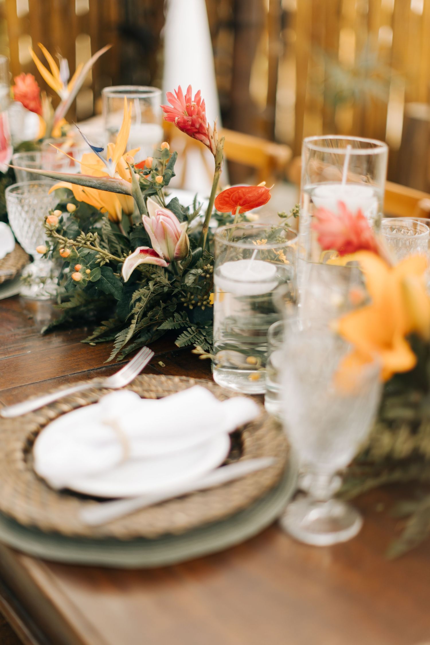 Elegant table setting with coral and orange floral centerpieces and crystal glasses.