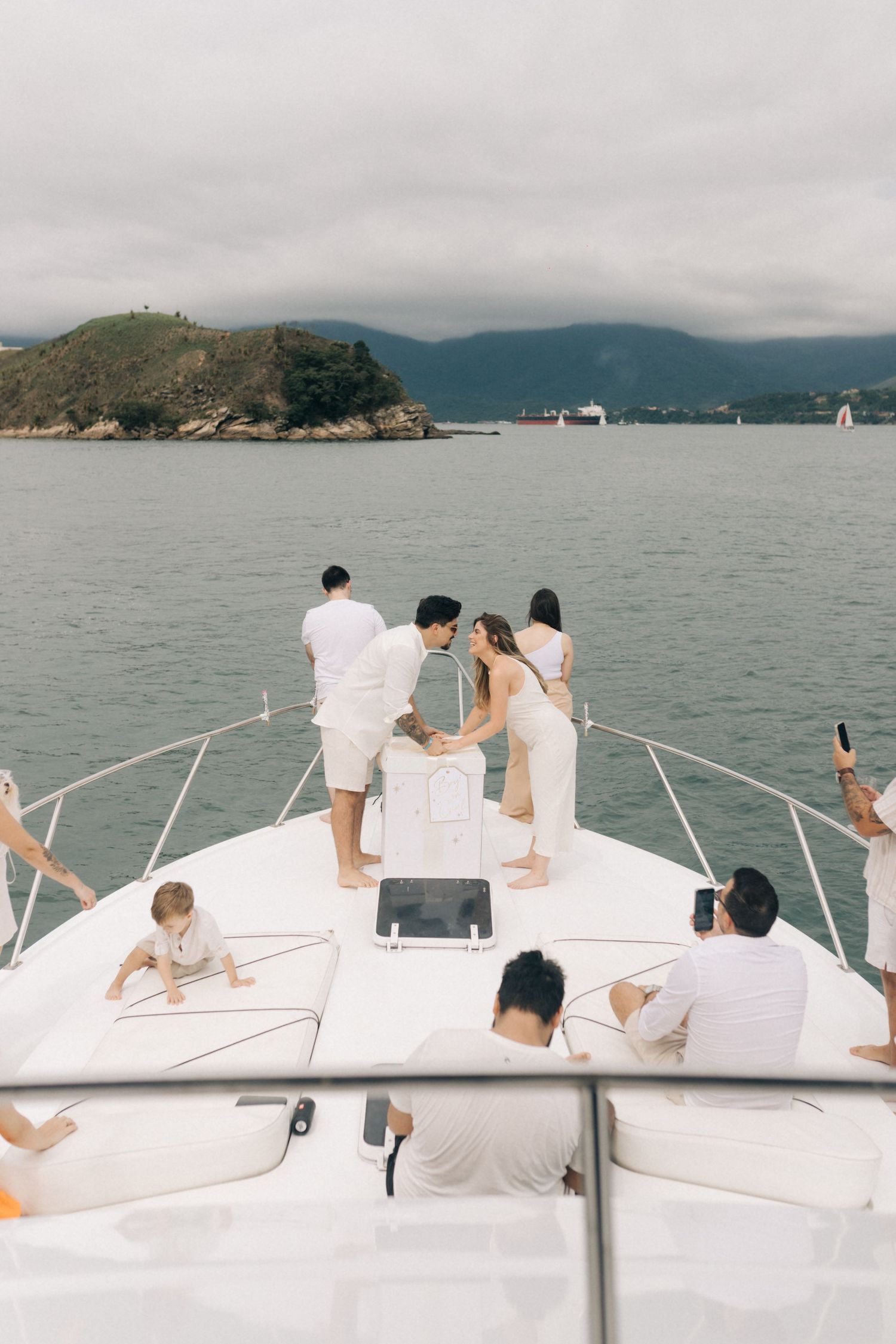 People relaxing on a white yacht deck with mountains and water views in the background.