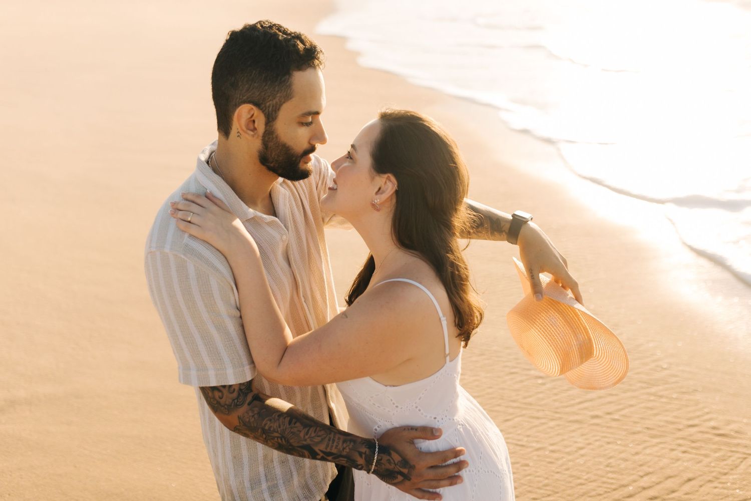 A couple shares an intimate moment on the beach during sunset.
