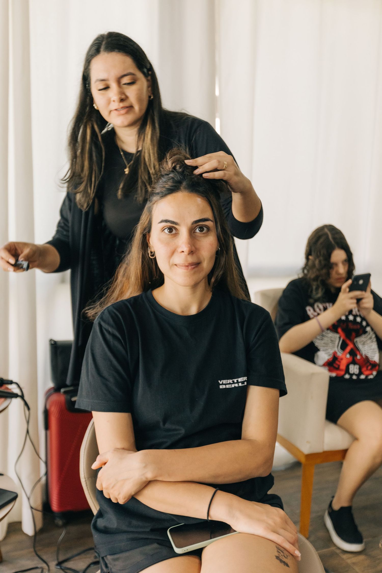 Beauty professionals in black uniforms prepare for styling services in a bright salon.